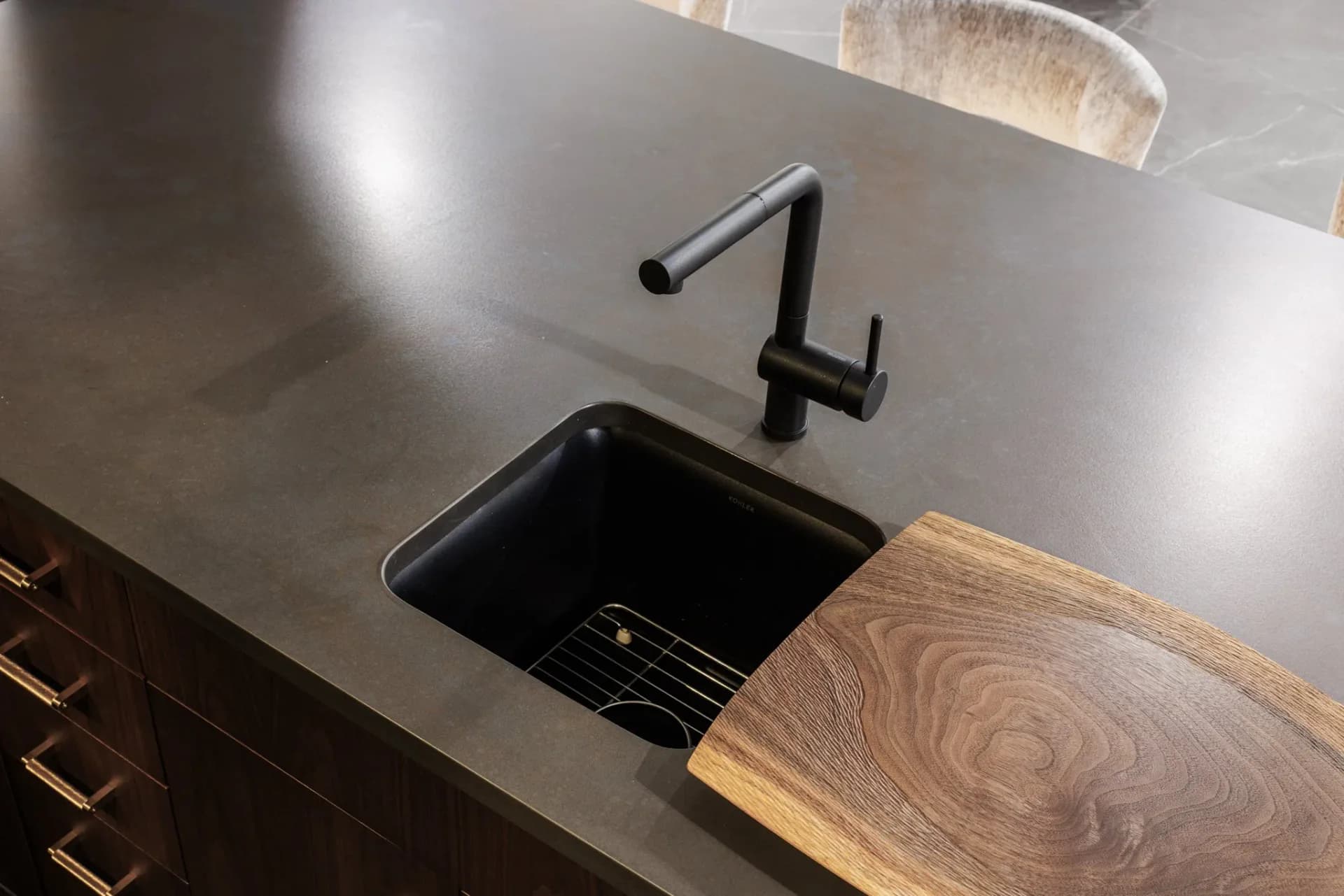 Modern bathroom sink detail with black undermount basin, minimalist stainless steel countertop, and sculptural black faucet fixture by Ipek Kaypak.