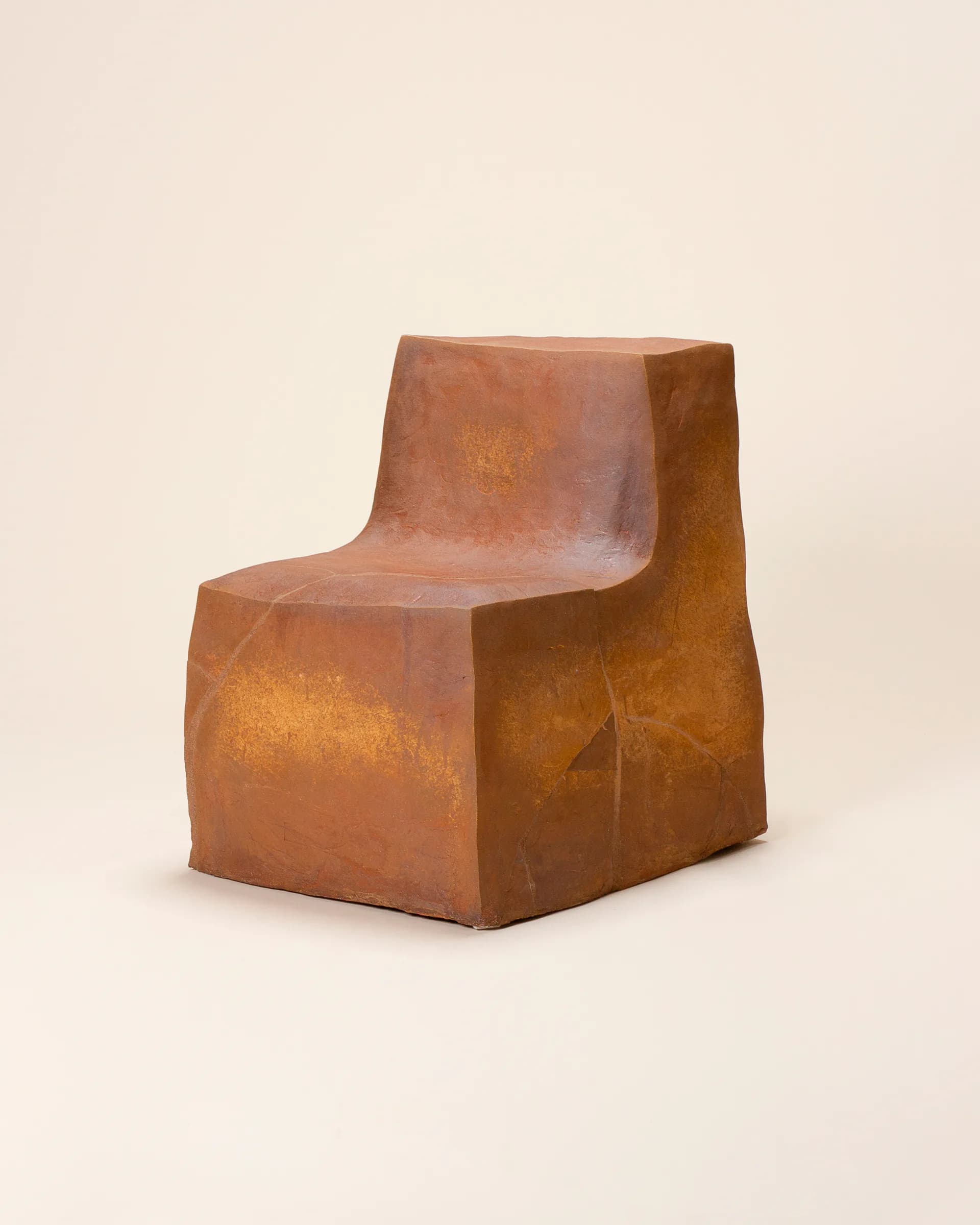Terracotta-colored sculptural chair with curved, organic forms and weathered surface finish by Isabel Rower.