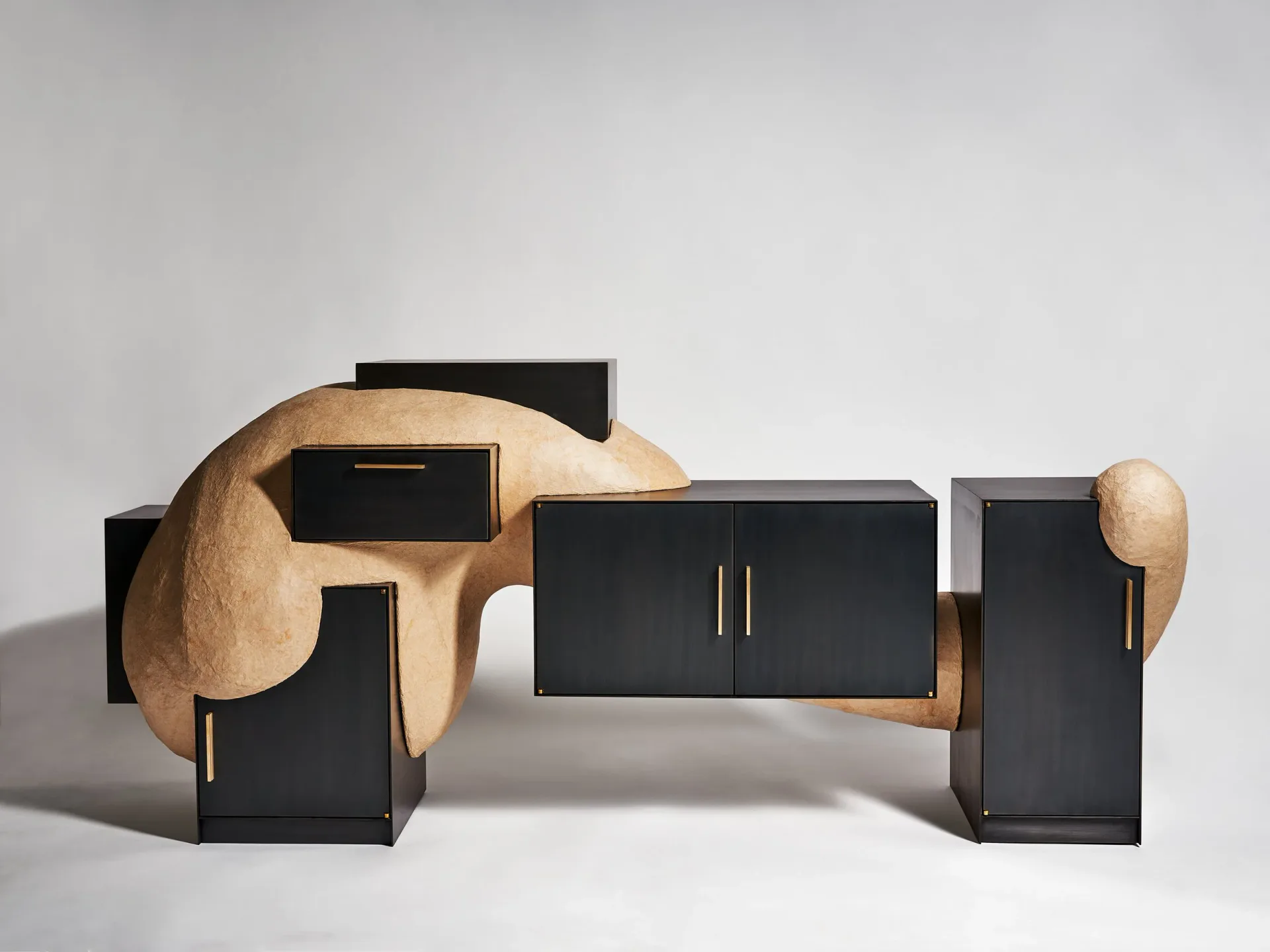 Abstract furniture composition featuring curved wooden forms paired with geometric black metal pieces against a neutral backdrop, by J McDonald.