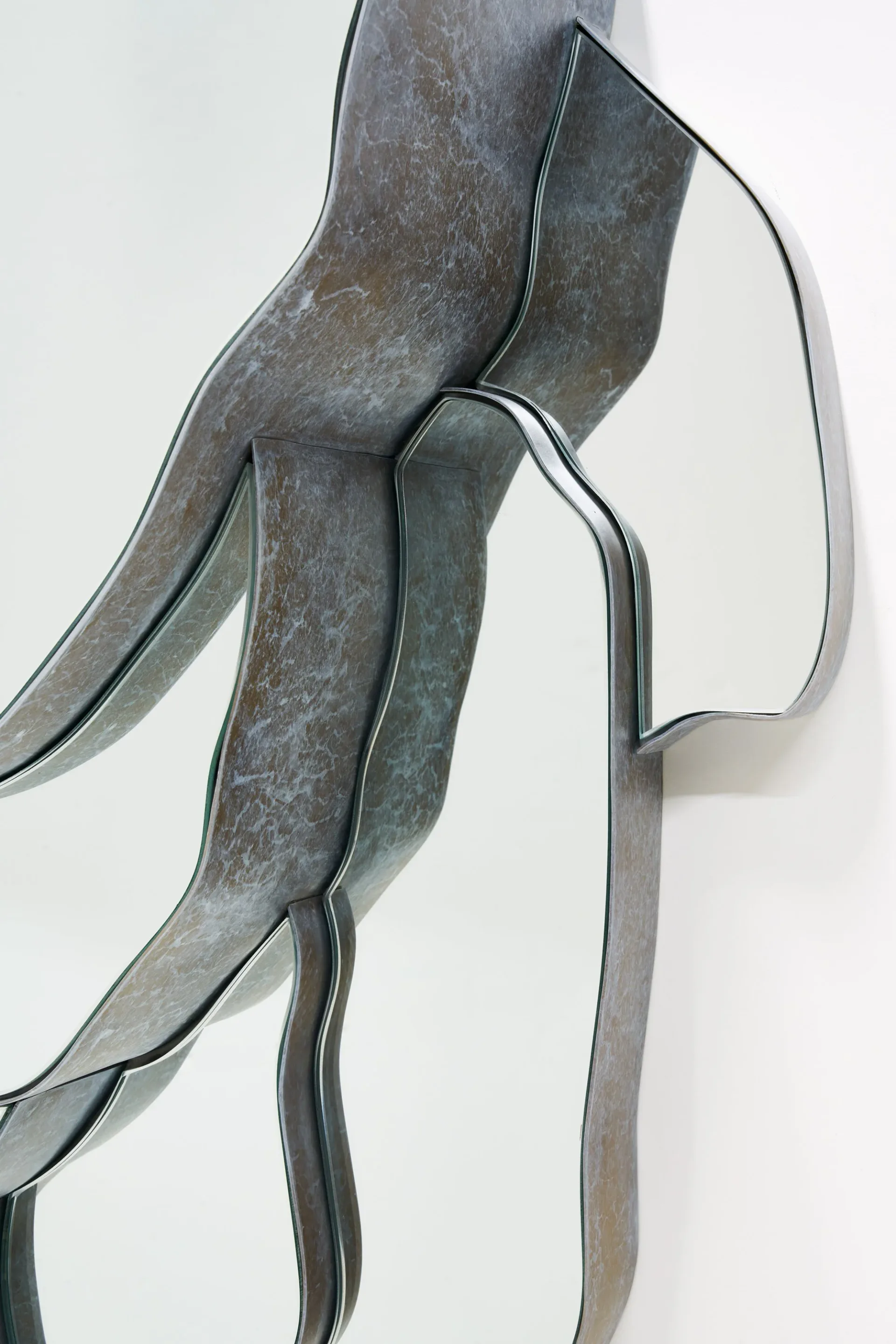 Abstract metal wall sculpture with curved, organic forms in weathered steel, creating flowing lines and negative space by J McDonald.
