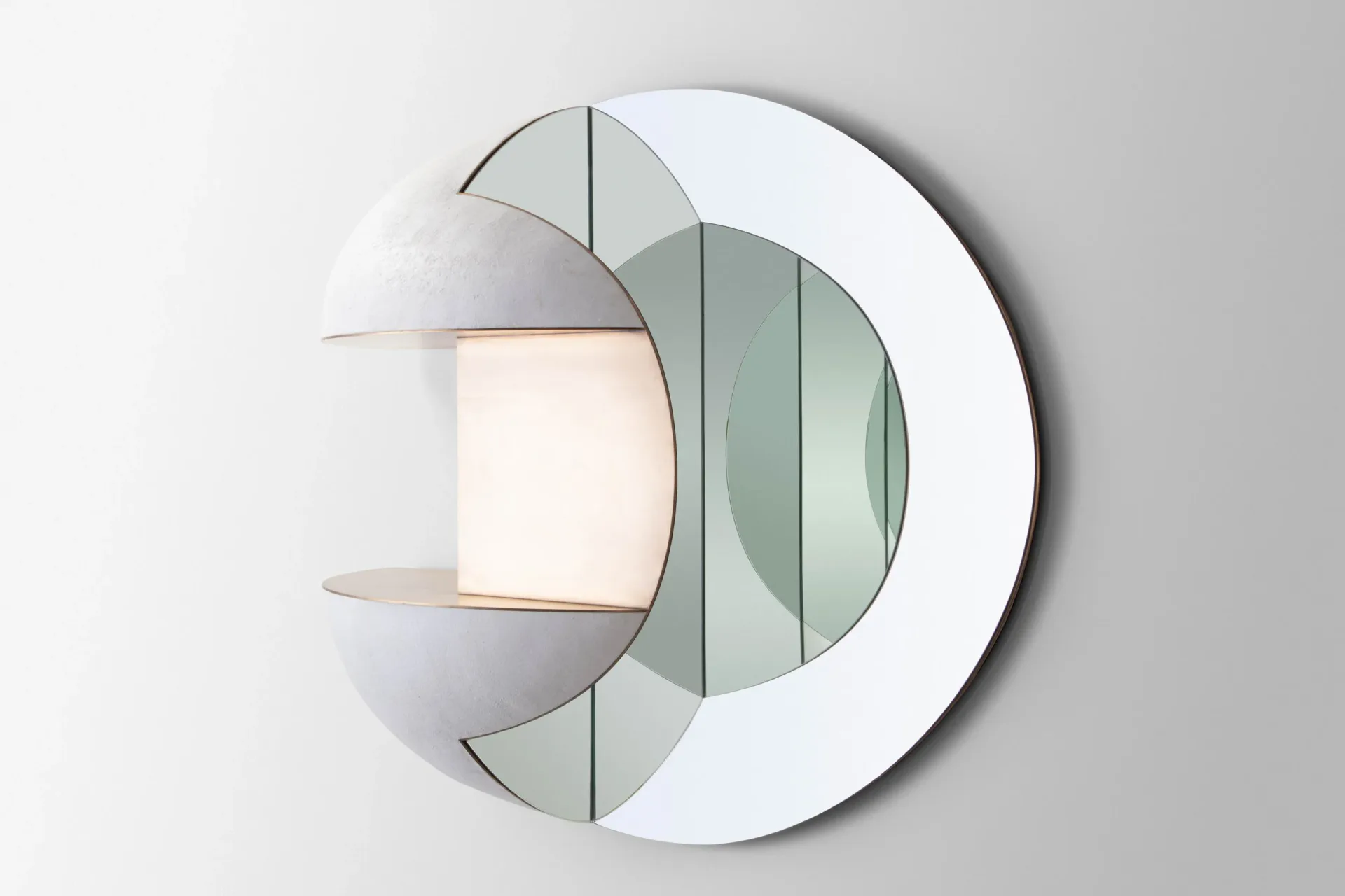 Modern wall sconce with layered geometric forms in white and sage green, featuring a glowing central element, design by J McDonald.