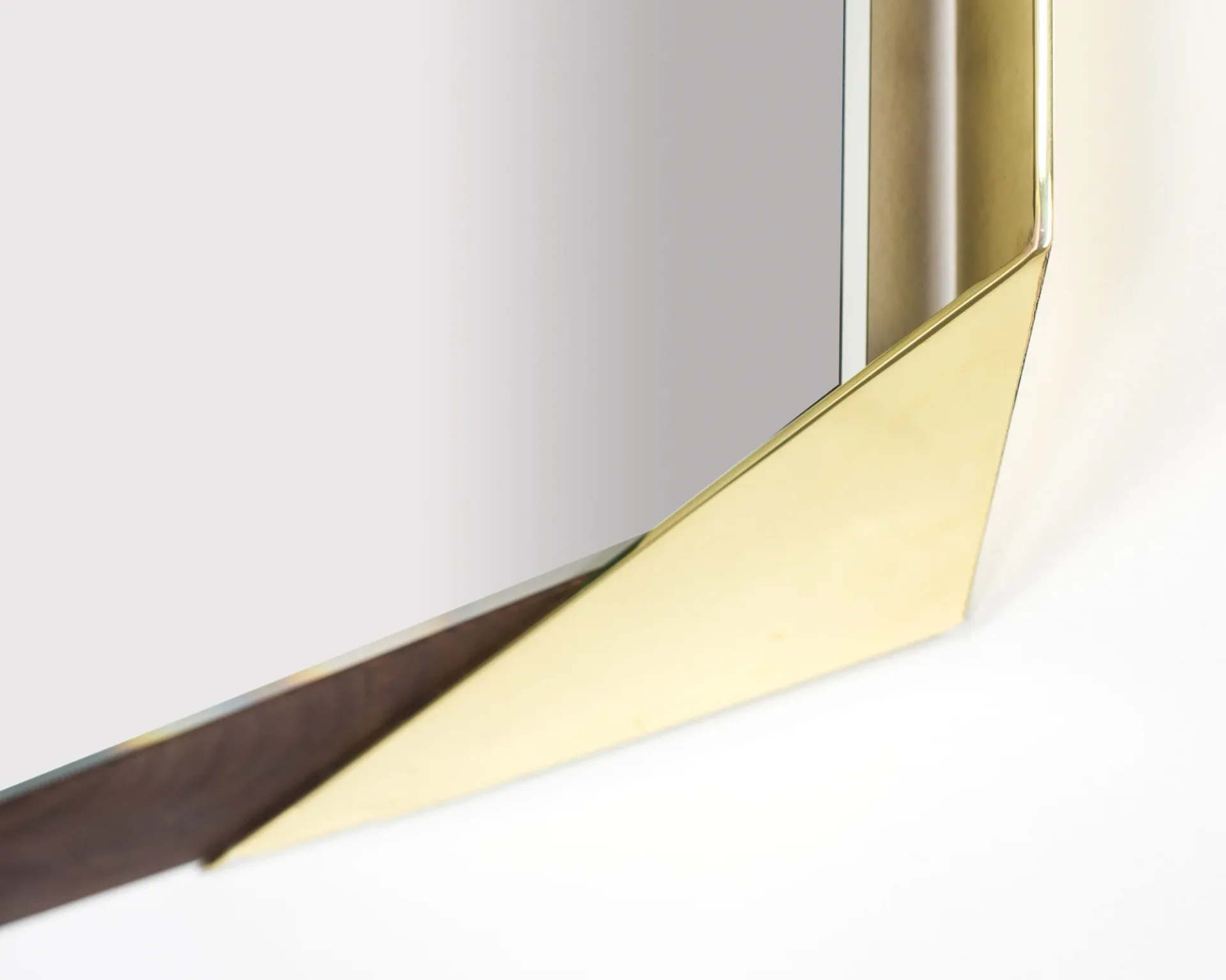 Abstract detail of a curved brass or gold-toned metal element against white and gray surfaces, showcasing material and light interplay by Jack Eriksson.