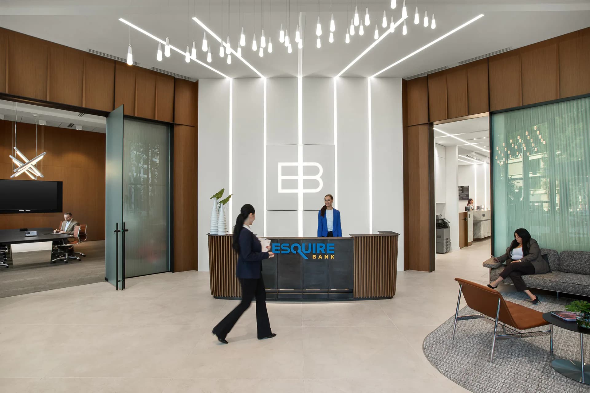 Modern corporate lobby with linear ceiling lights, wood-paneled walls, central reception desk with EB logo, and synthetic figures, designed by Jaclyn Letsch.
