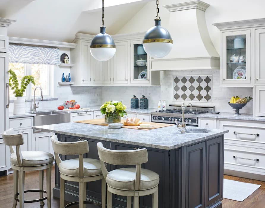 A bright, modern white kitchen with marble countertops, black island, diamond-patterned backsplash, and pendant lighting by Jacquelyn Lagravinese.