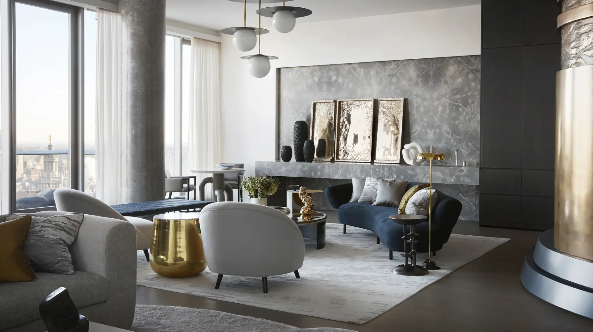 Modern living room with gray curved seating, dark accent wall, pendant lighting, and floor-to-ceiling windows by Jamie Drake.