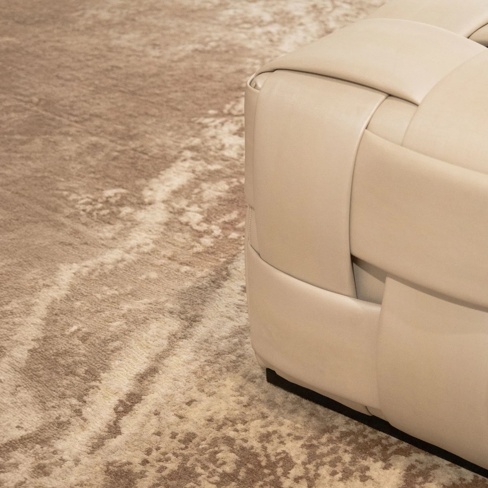 Cream upholstered seating detail beside textured taupe carpet in an interior space by Janis Provisor.