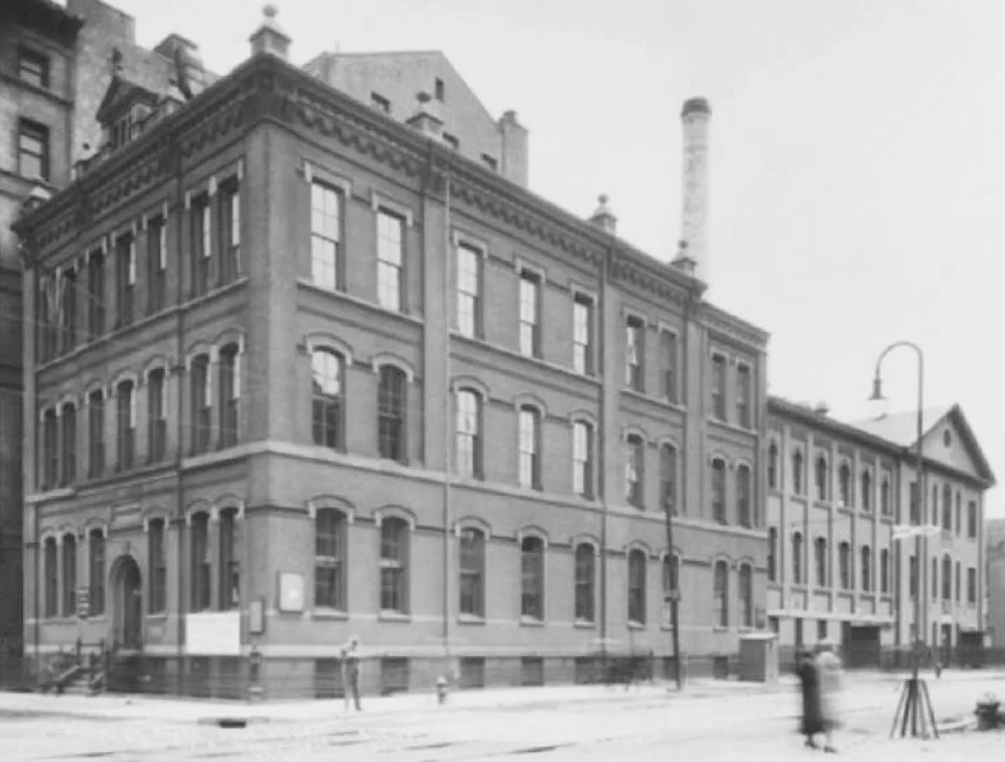 Historic masonry building with ornamental detailing and large window grid, street-level facade by Jared Della Valle.