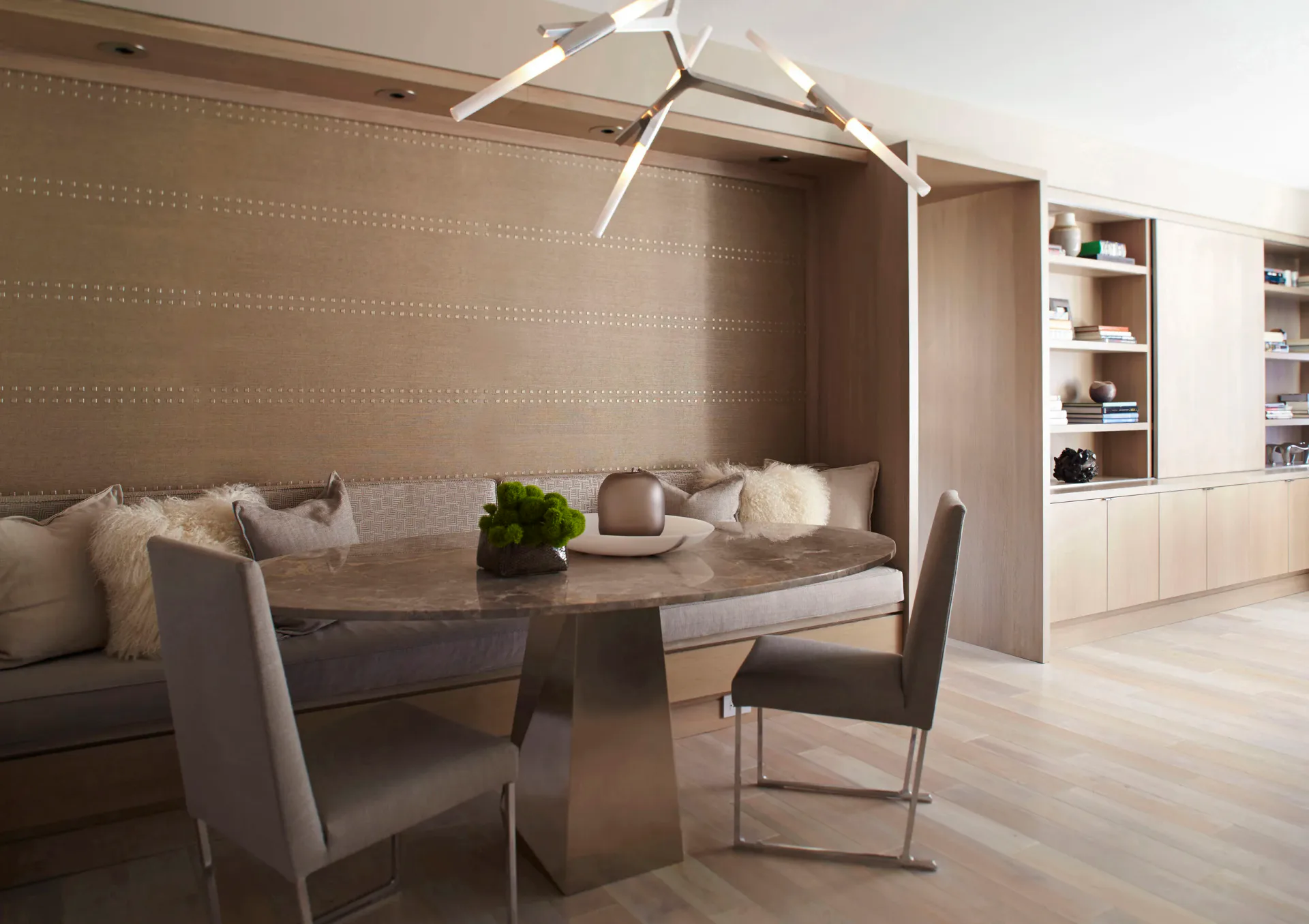 Modern dining area with canopy bed feature, taupe upholstered banquette, glass-top table, and built-in shelving in neutral palette by Jasmine Lam.