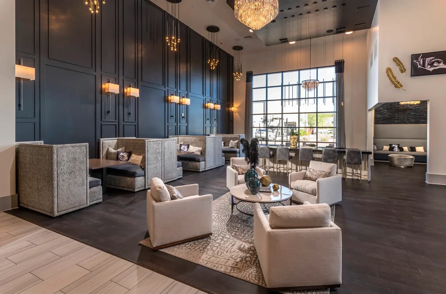 Modern luxury lounge with navy paneled walls, cream upholstered seating, dark wood flooring, brass pendant lighting, and expansive windows by Jasmine Moon.