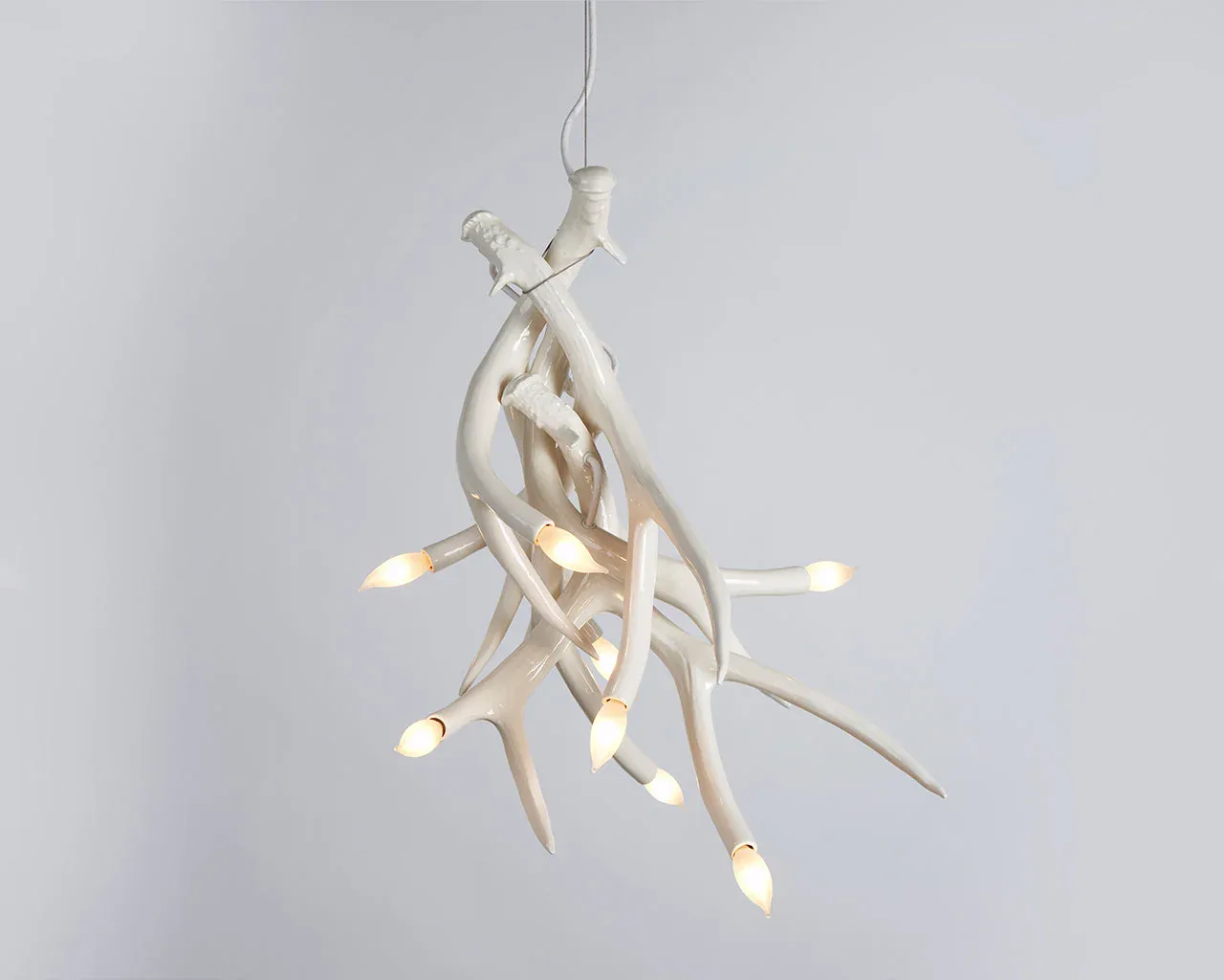 Sculptural hanging pendant light fixture with organic branch-like white forms and integrated LED bulbs, suspended against neutral background by Jason Miller.
