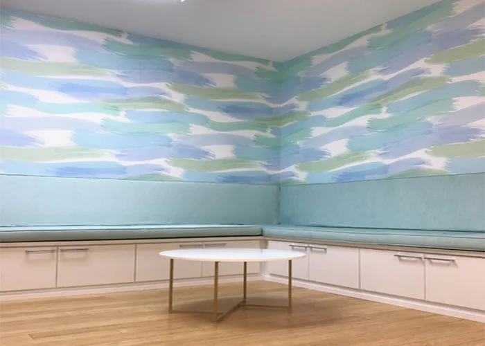 Minimalist gallery interior with light blue walls, pale pink cabinetry, and an abstract ceiling featuring blue and green flowing patterns above a round table by Jean Herron.