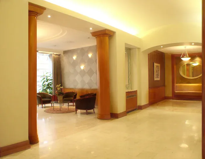Modern lobby interior with polished marble floors, wood columns, warm ambient lighting, and contemporary furnishings by Jeanne Isaacson.