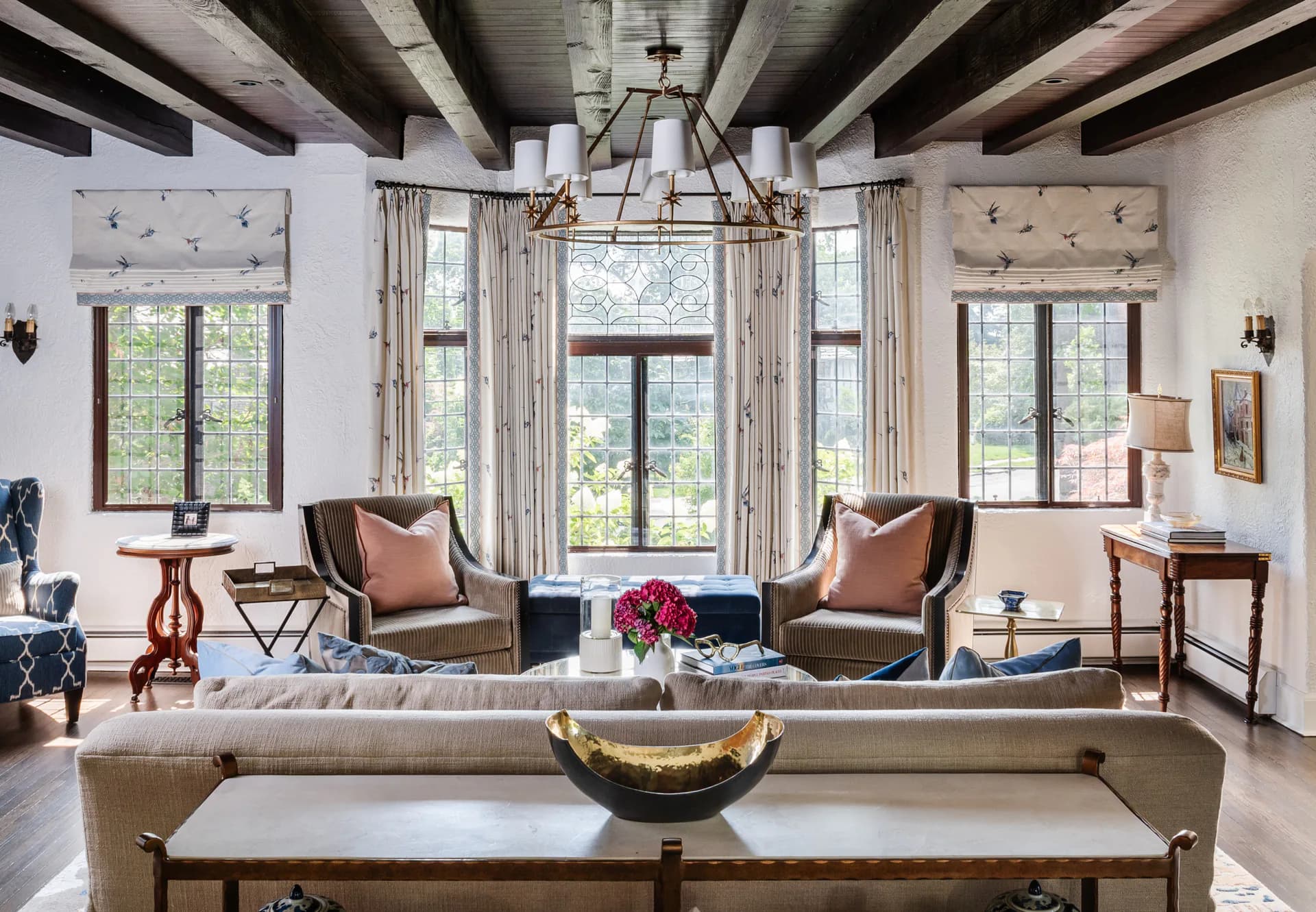 Modern living room with exposed concrete ceiling beams, neutral upholstery, bronze sculpture, and floor-to-ceiling windows overlooking landscaping by Jen DeLalio.