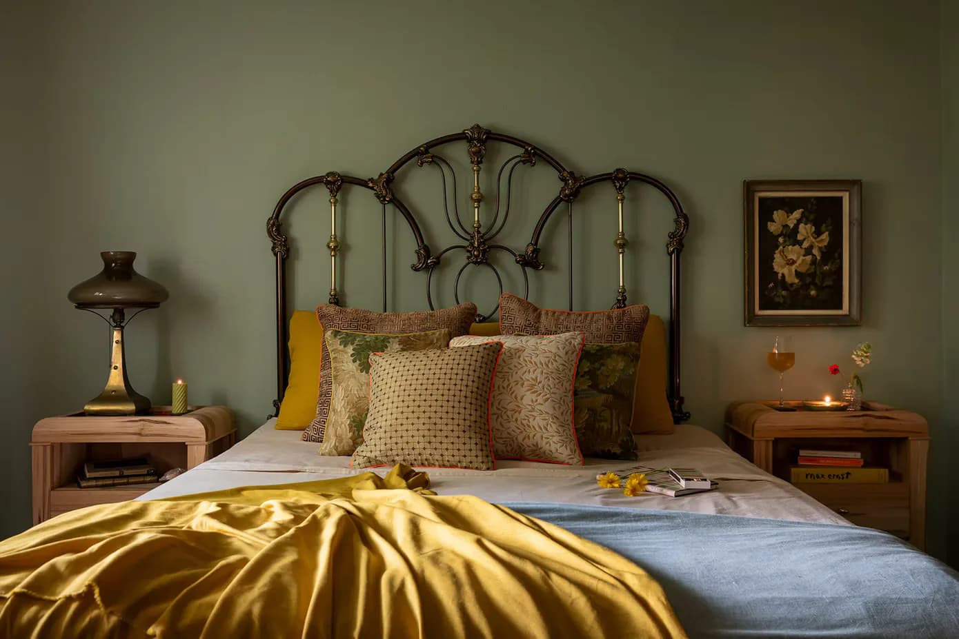 Master bedroom with ornate metal headboard, gold silk bedding, beige patterned pillows, and warm wood nightstands by Jennifer Salvemini.