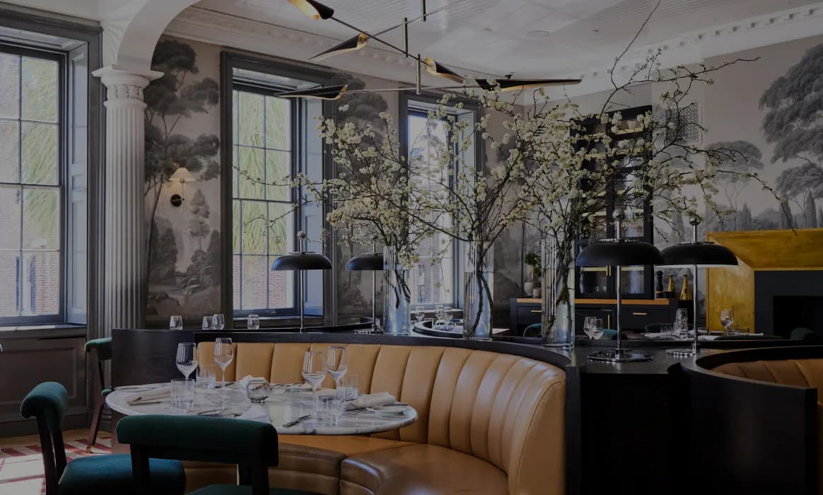 Contemporary restaurant interior with curved mustard banquet seating, large windows, living trees, and artistic wall murals by Jennifer Tsai.