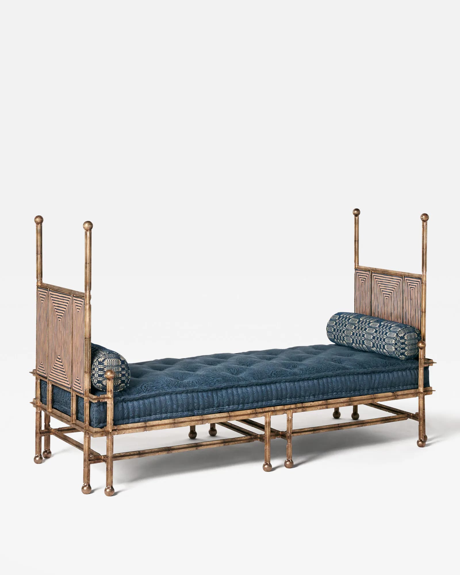 Wooden four-poster bed with blue upholstered mattress and decorative pillows, featuring carved headboard and footboard details, designed by Jeremy Anderson.