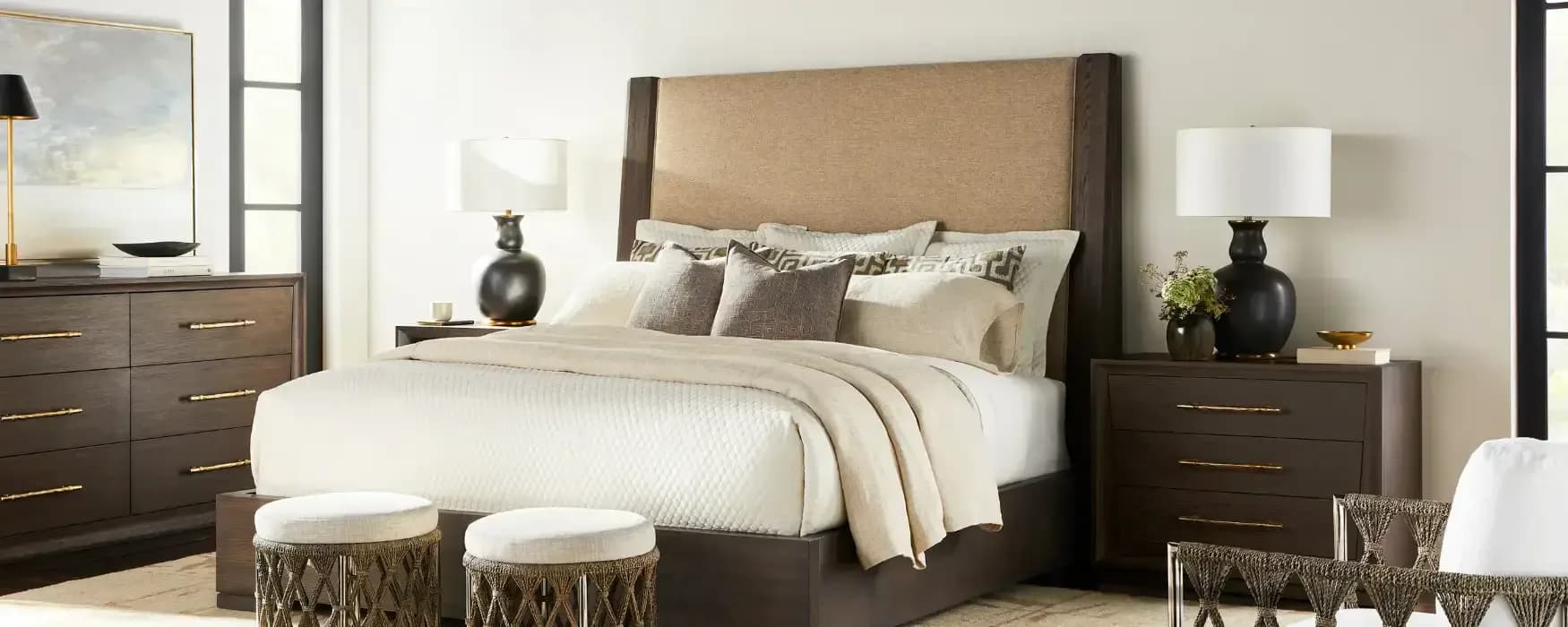 Upholstered bedroom with dark wood bed frame, neutral bedding, matching nightstands with black lamps, and coordinating dresser by Jerry Rock.