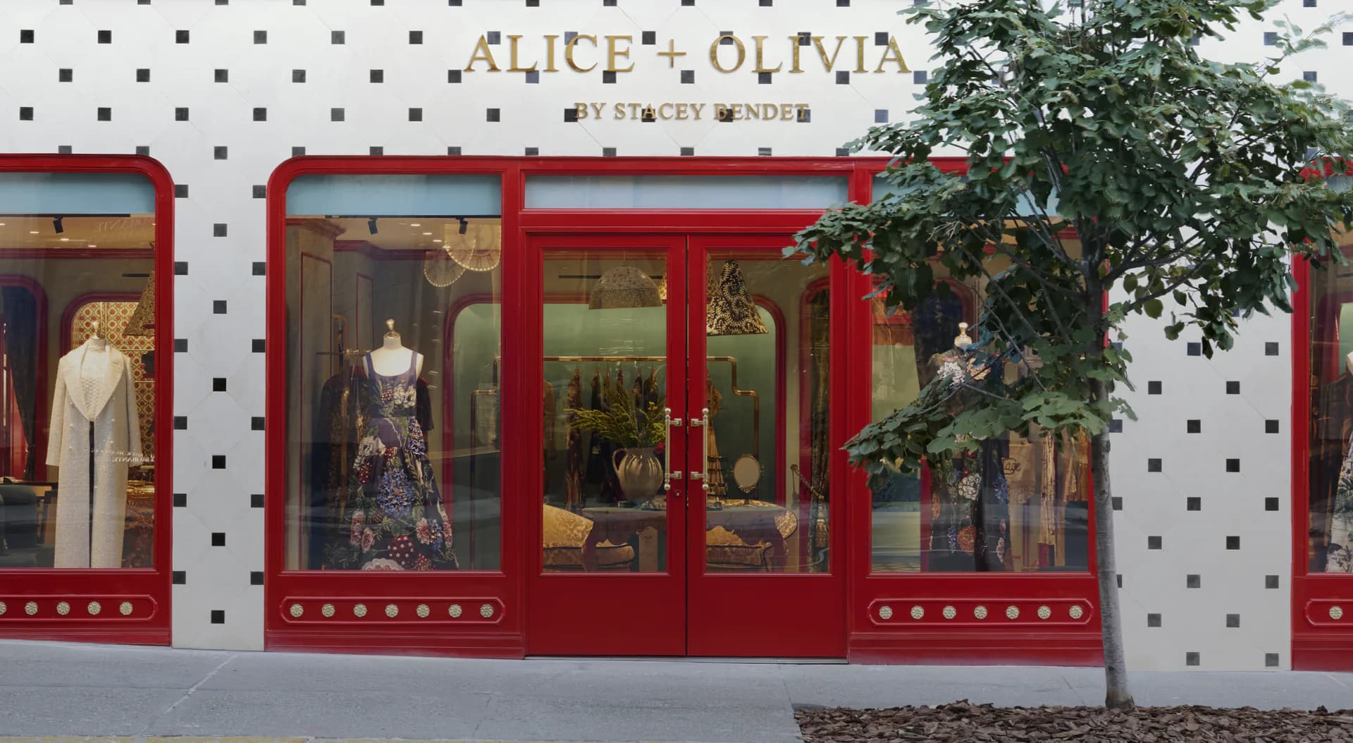 Alice + Olivia storefront with red-framed windows, white polka-dot facade, and climbing ivy by Jess Nahon.