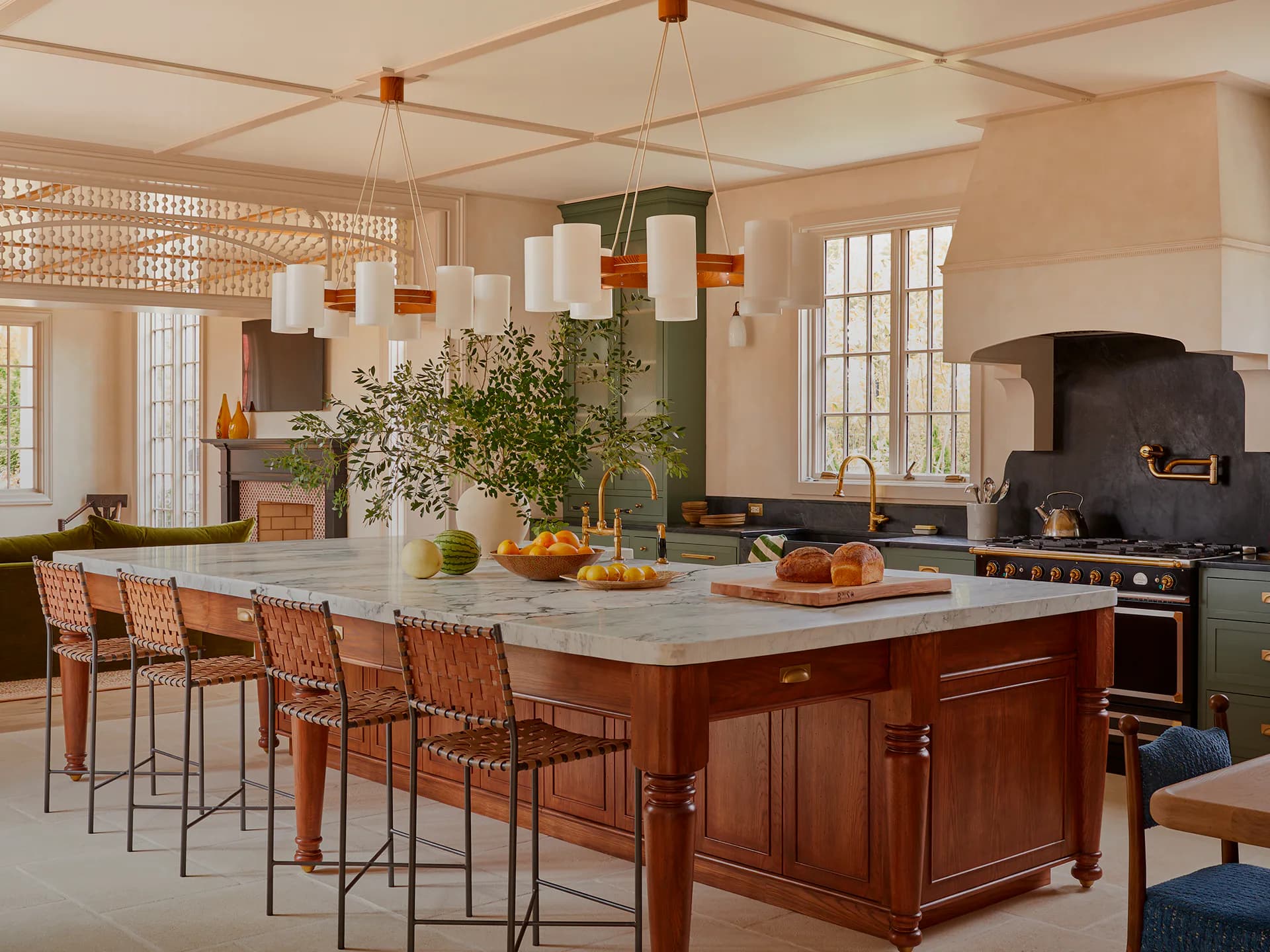 Warm contemporary kitchen with wooden island, marble countertop, pendant lighting, and sage cabinetry by Jess Nahon.
