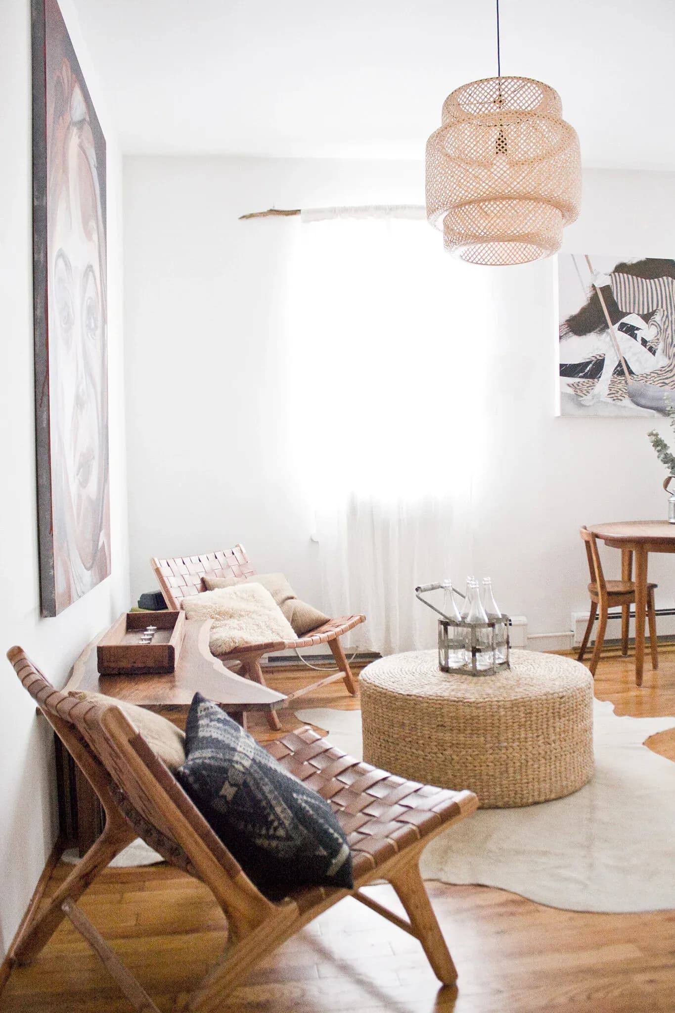 Minimalist living room with natural wood furniture, woven pendant lamp, and neutral palette, designed by Jesse Elliott.