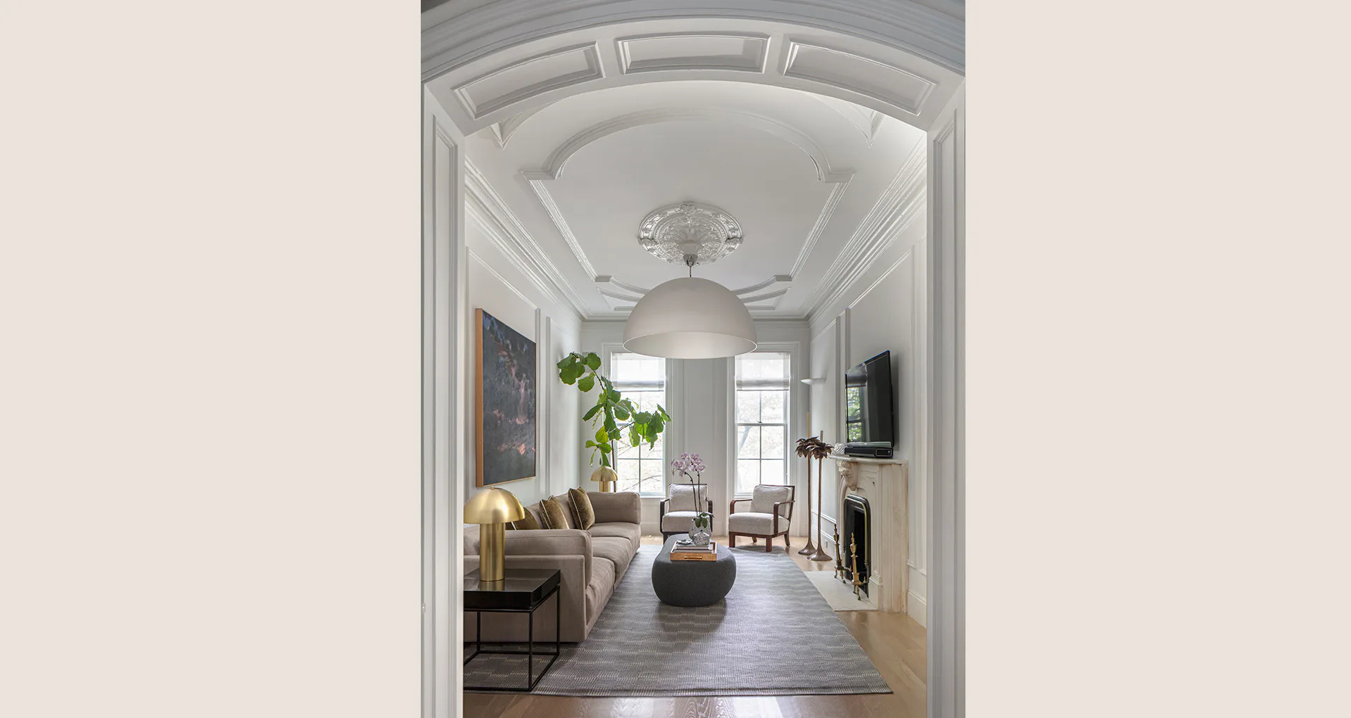 A bright, elegantly proportioned hallway with coffered ceiling, arched doorway, potted plant, and contemporary furnishings visible through the passage by Jessica Siegel.