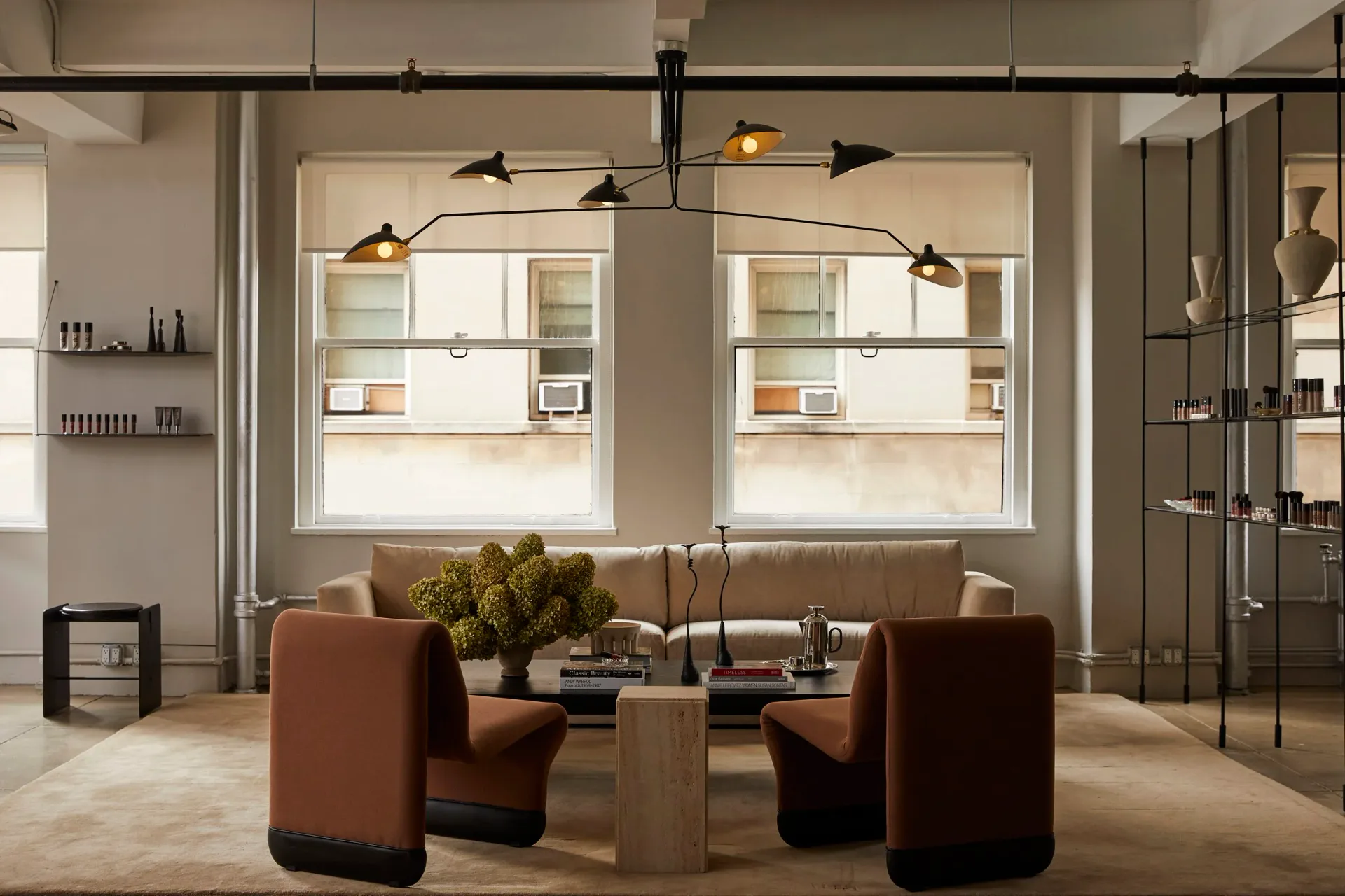Modern interior showroom with cognac leather seating, brass pendant lights, and floor-to-ceiling shelving, designed by Jessica Werner.
