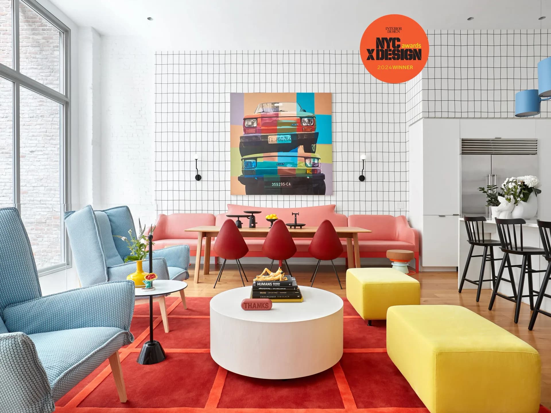 Colorful modern living room with red sofa, yellow ottomans, blue armchair, white round coffee table, and abstract artwork on grid-tiled wall by Johanna Keller.