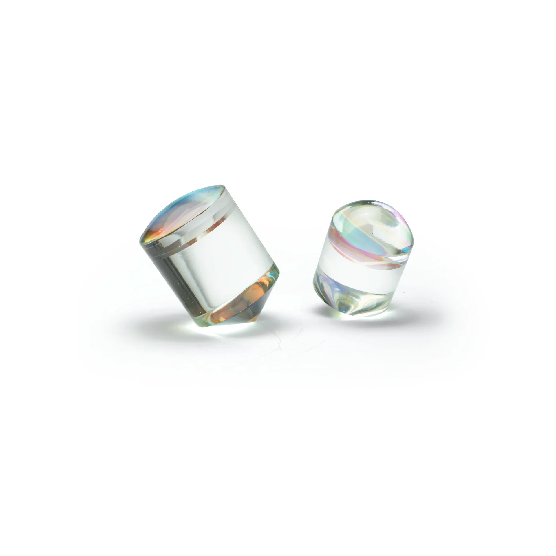 Two transparent glass cylinders with iridescent light refractions and subtle shadows, product design by John Hogan.