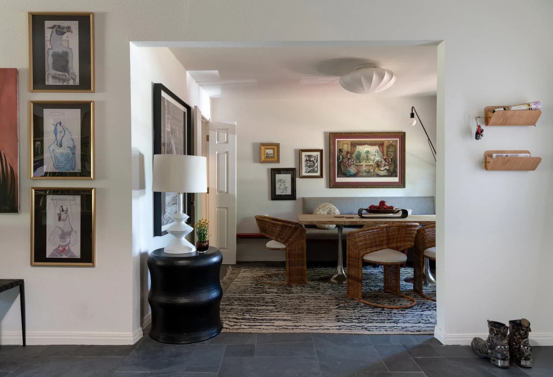 Open-concept living and dining area with warm wood furnishings, neutral palette, framed artwork, and woven accents designed by Jonah Kilday.