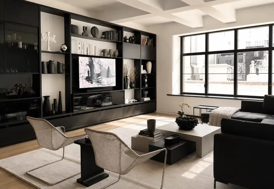 Modern living room with black media wall, white ceiling beams, neutral seating, and floor-to-ceiling windows by Jordan Jones.