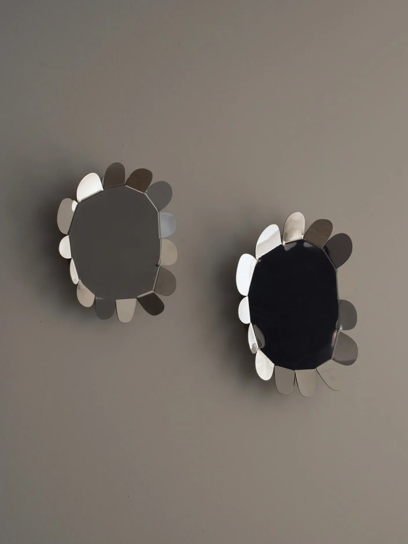 Two sculptural wall installations featuring dark oval forms surrounded by radiating white and gray geometric elements, creating organic three-dimensional compositions by Jorge Suárez-Kilzi.