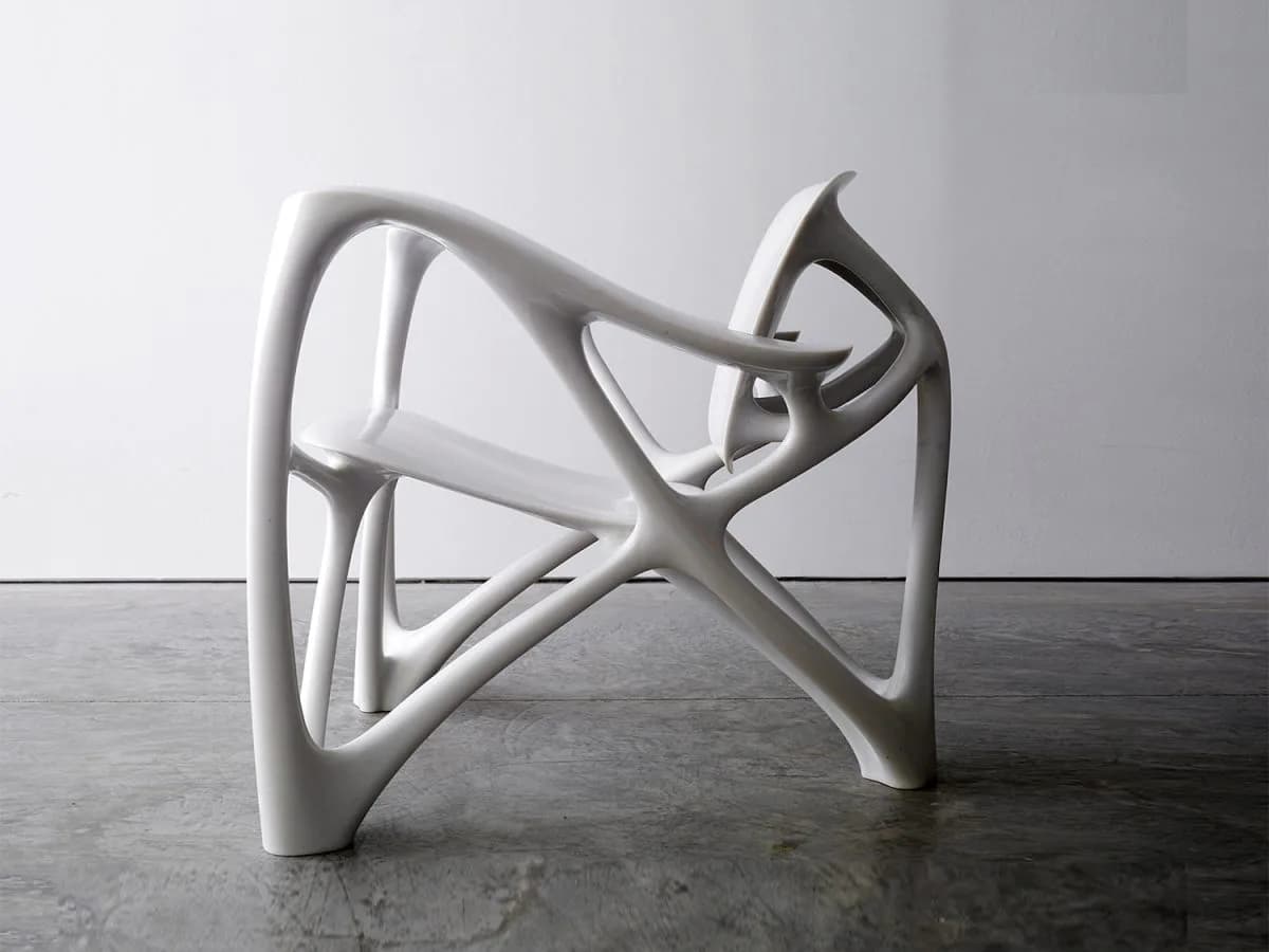 White sculptural abstract form with interlocking curved and angular elements on dark concrete surface by Joris Laarman.