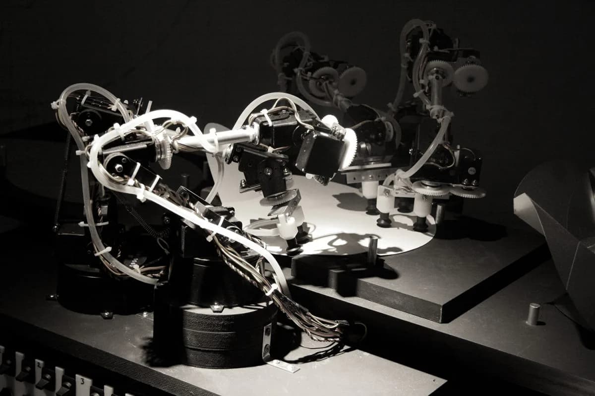 Kinetic robotic sculpture with articulated mechanical arms and white neon lighting against dark background, a dynamic installation piece by Joris Laarman.