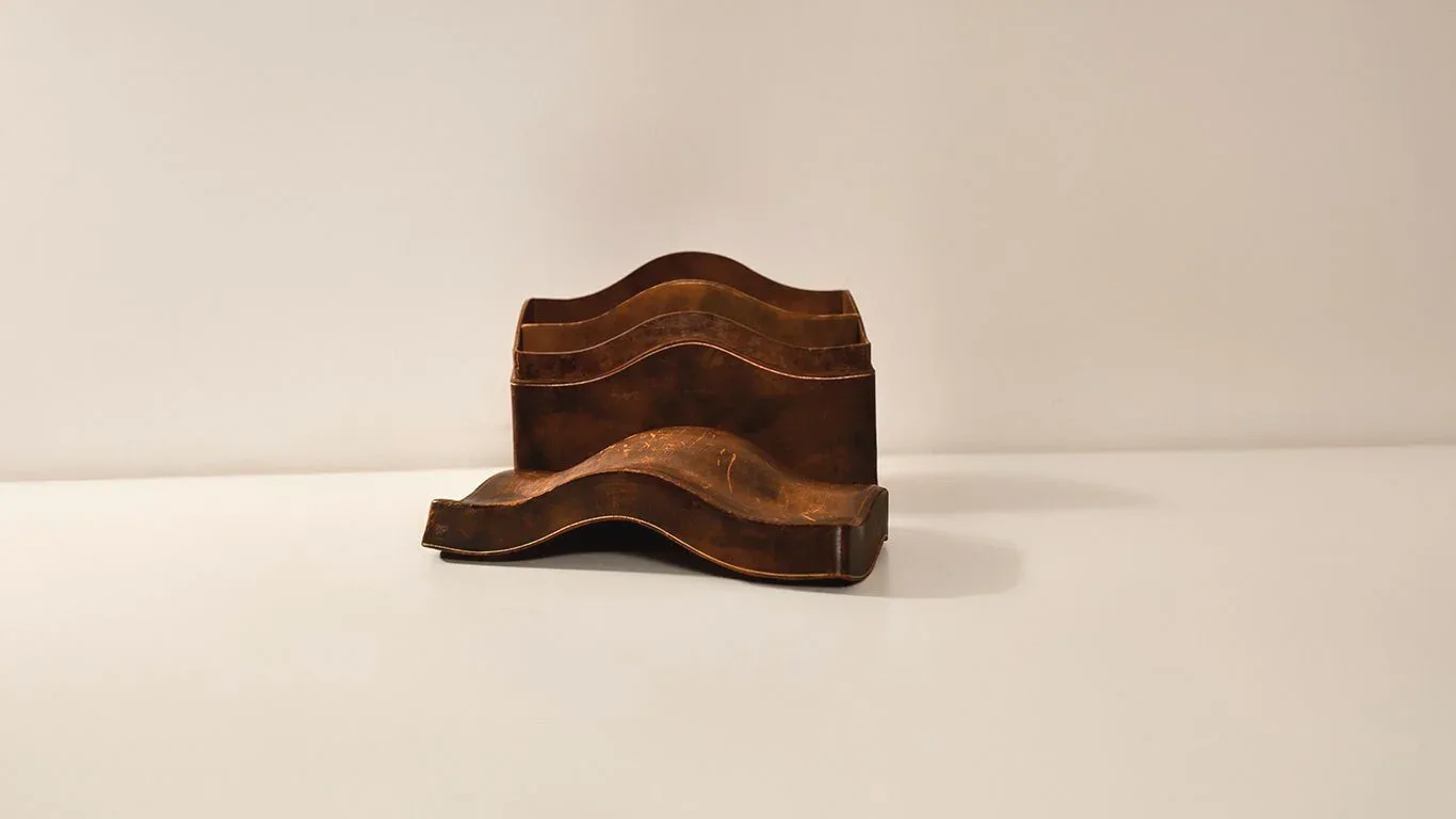 Sculptural wooden furniture pieces with curved, wave-like forms in warm brown tones arranged on a neutral surface, by Juan Russo.