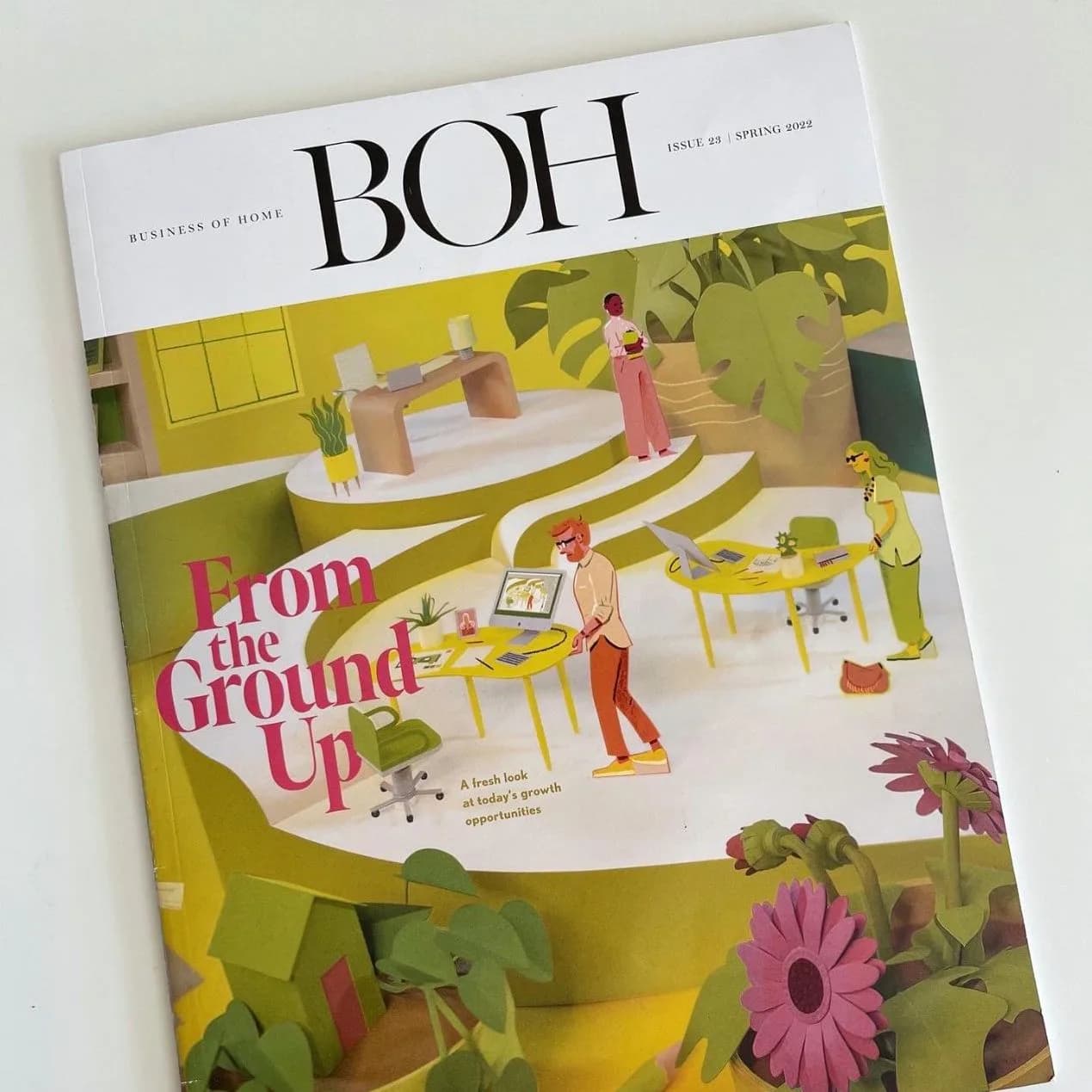 Magazine cover featuring a bright yellow and green interior space with illustrated figures, plants, and furniture designed by Juanita Jimenez.