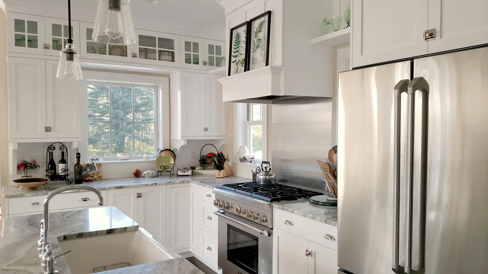 Bright, modern white kitchen with stainless steel appliances, white cabinetry, subway tile backsplash, and large windows, designed by Judi Price.
