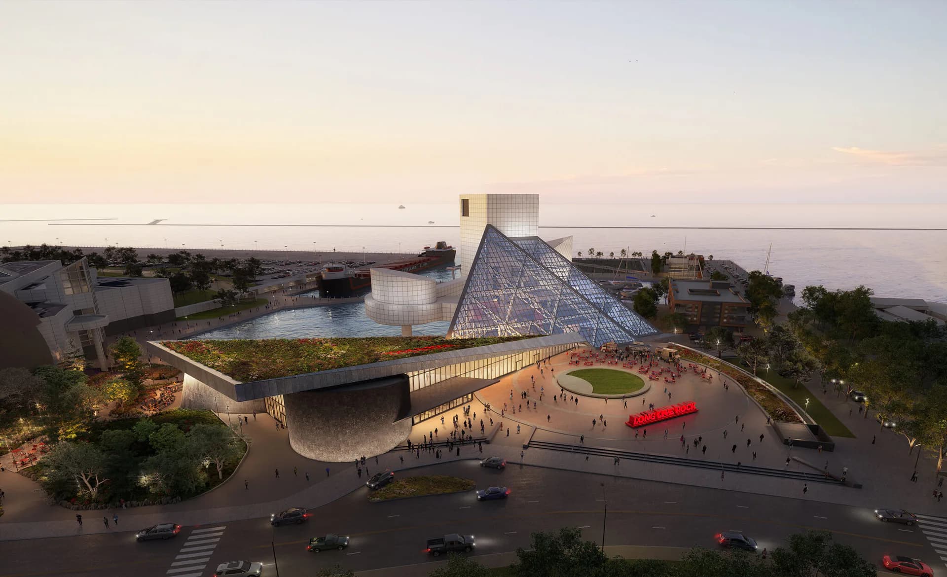 Waterfront cultural building with pyramidal roofline, curved plaza with red sculptural element, and populated grounds at dusk by Julia Lewis.