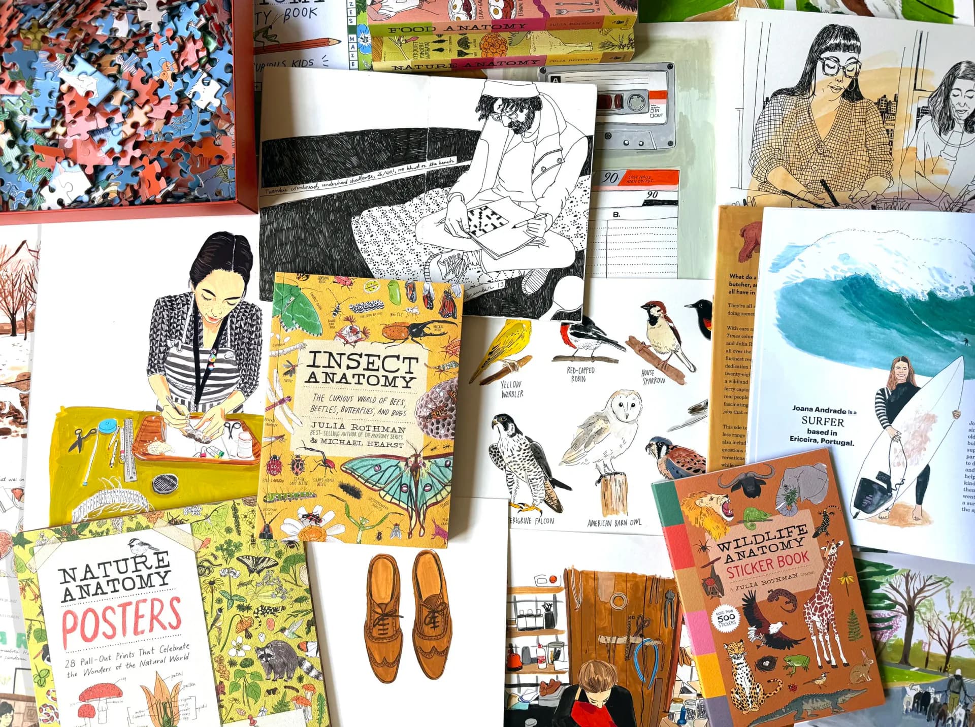 Flat lay of Julia Rothman's illustrated and printed design work including colorful posters, books, drawings, and decorative objects arranged on a white surface.