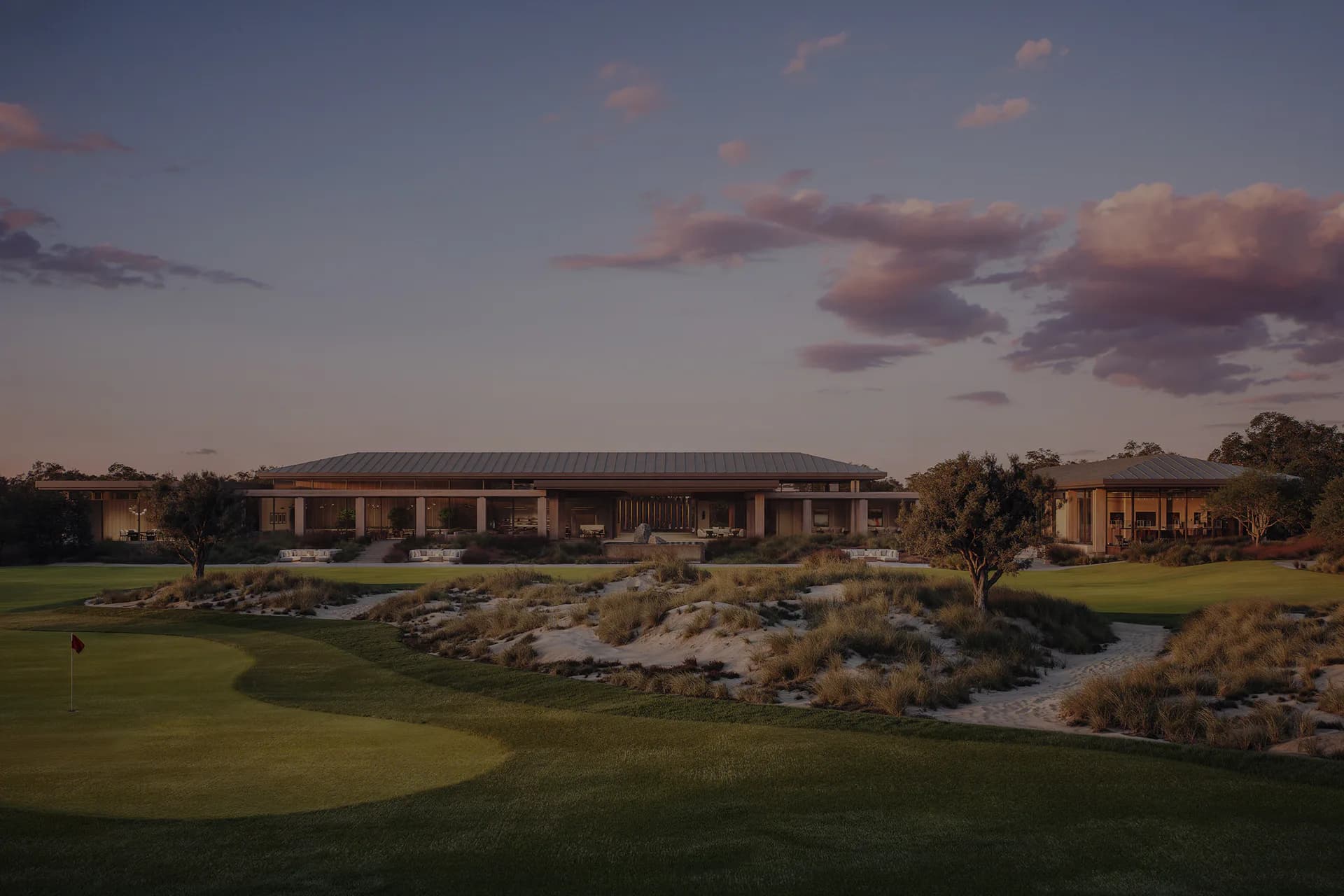 Golf course clubhouse at dusk with manicured greens, water features, and native plantings designed by Julia Turner.