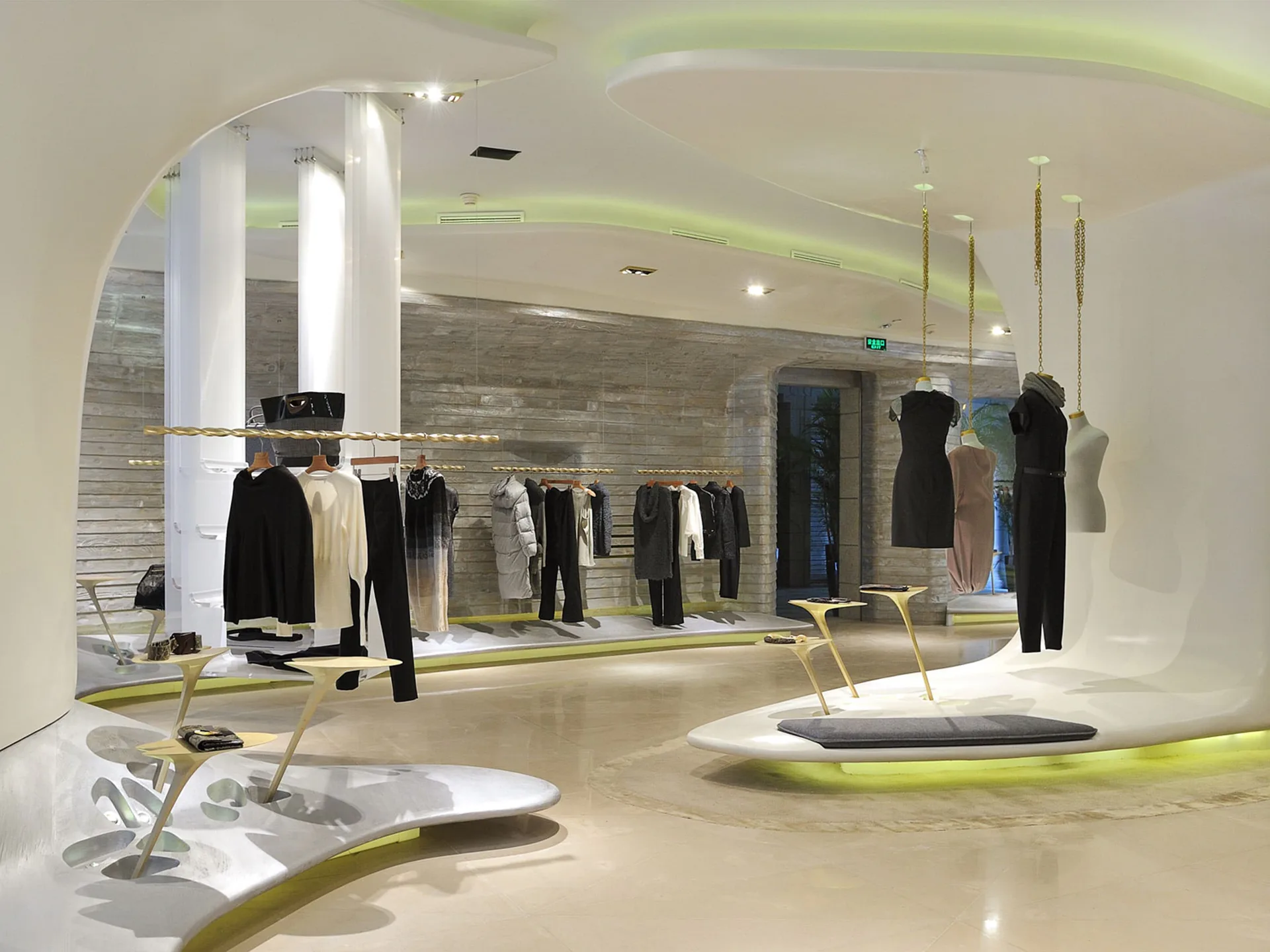 Modern retail clothing store with curved white columns, pale wood flooring, lime-green accents, and minimalist display fixtures showcasing black apparel by Justin Korhammer.