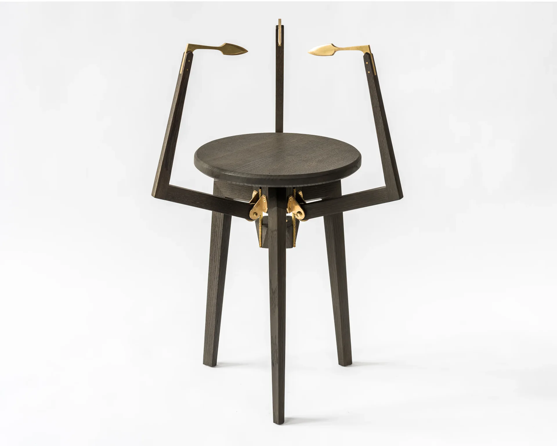 Dark metal sculptural table with brass accents and articulated arm details, featuring a circular top and three-legged base by Kai-wei Hsu.