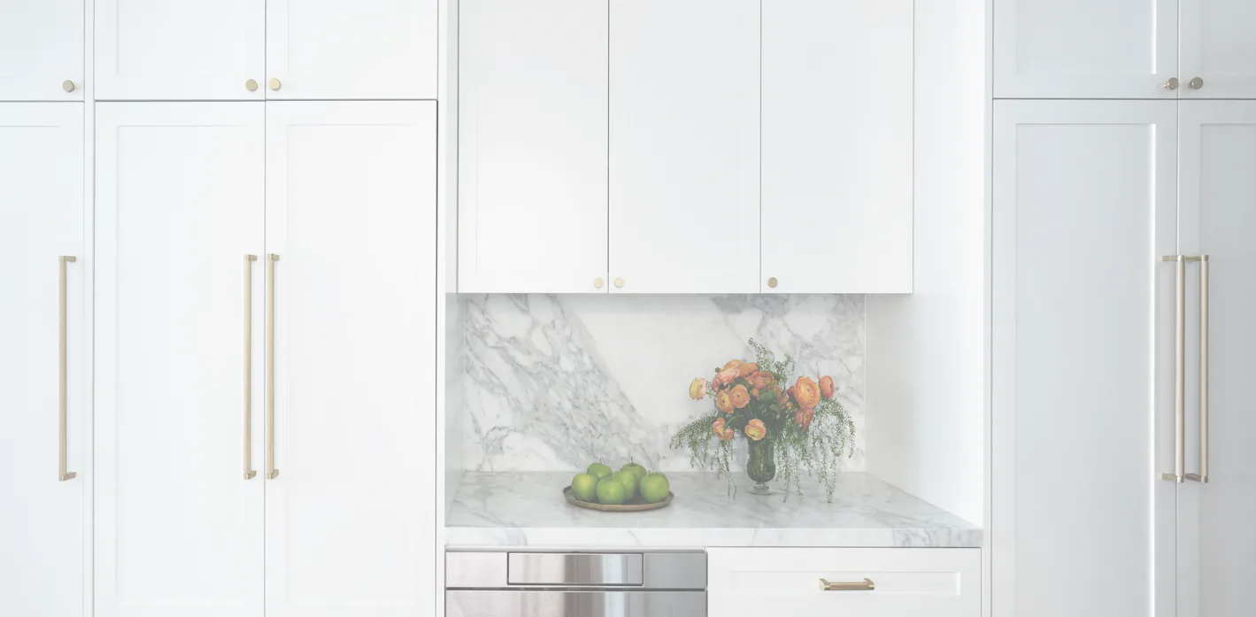 Modern white kitchen with marble backsplash, stainless steel appliances, and fresh flowers, designed by Karen Loc.