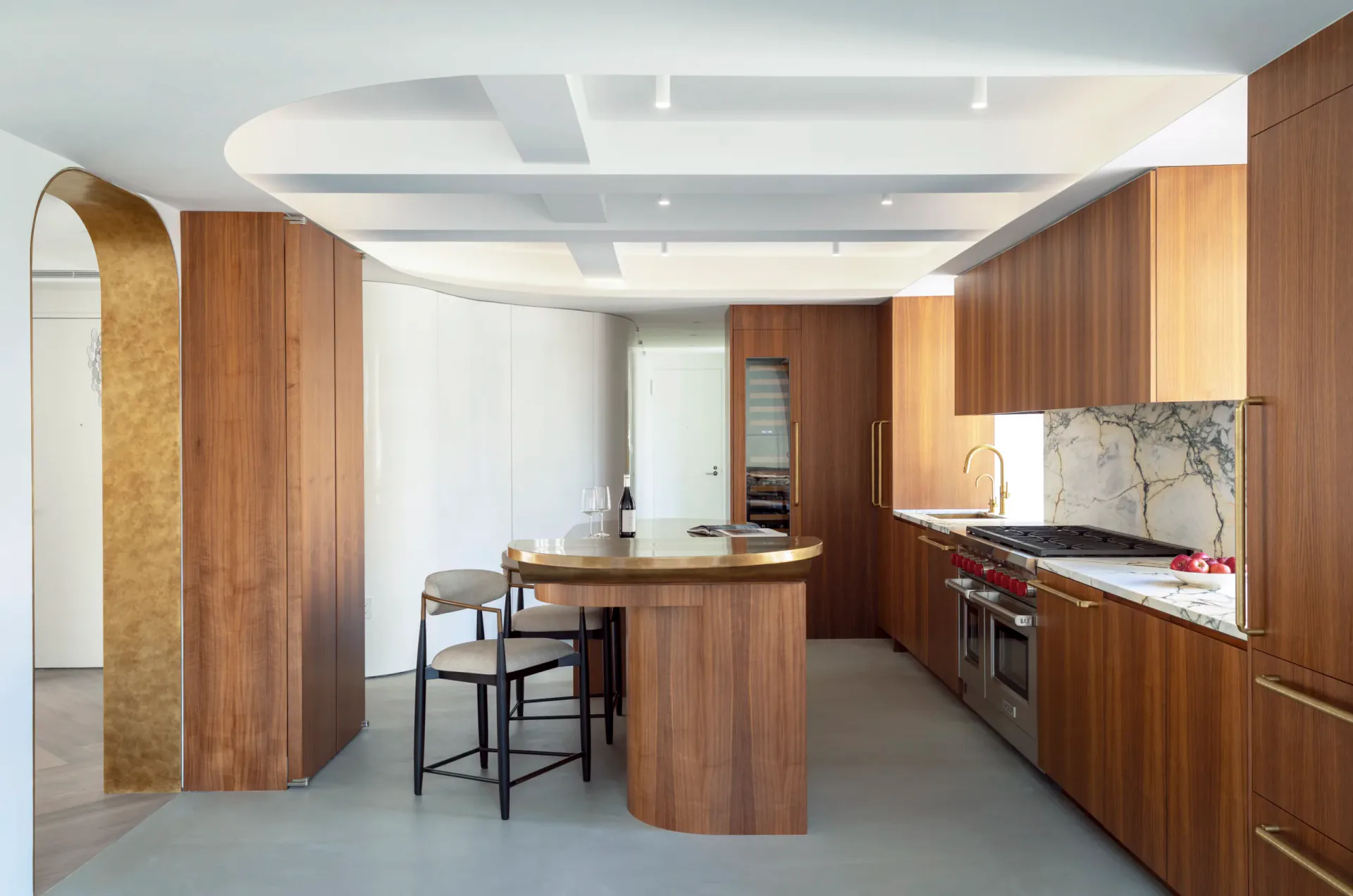 Modern kitchen with curved wood cabinetry, marble backsplash, and sculptural island featuring synthetic lighting and idealized proportions by Karin Kohlhaas.