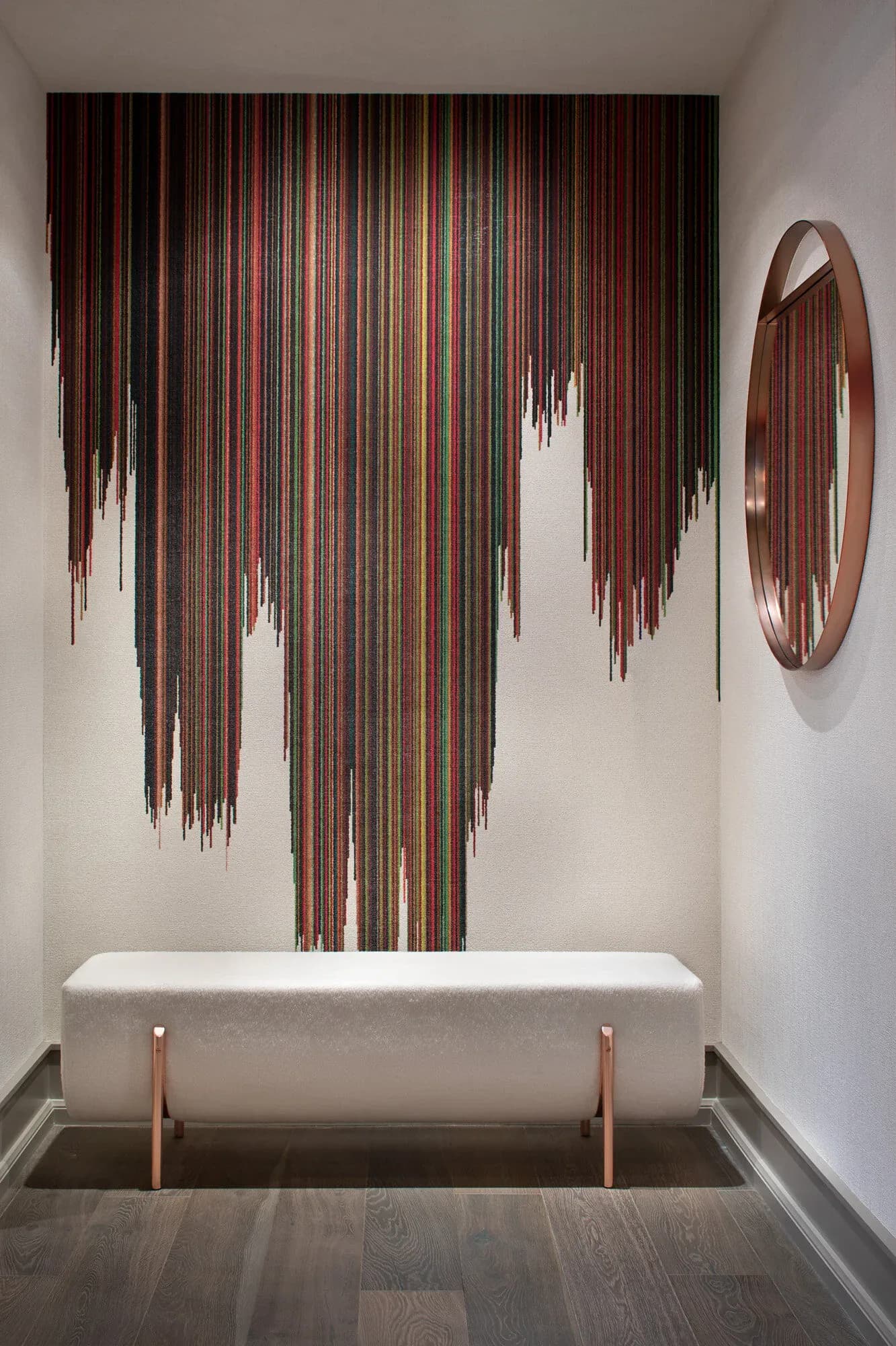 Minimalist bathroom with white soaking tub features cascading copper-wire art installation on wall and circular mirror by Kary Bell.