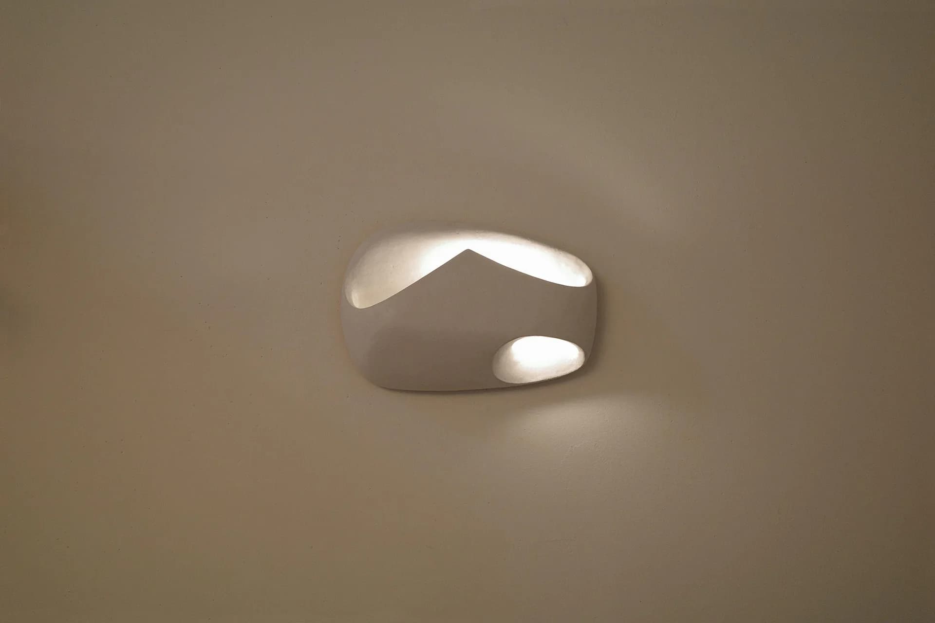 Abstract sculptural form with smooth curved surfaces and organic openings, rendered in soft gray and white tones with ethereal lighting by Kassandra Thatcher.