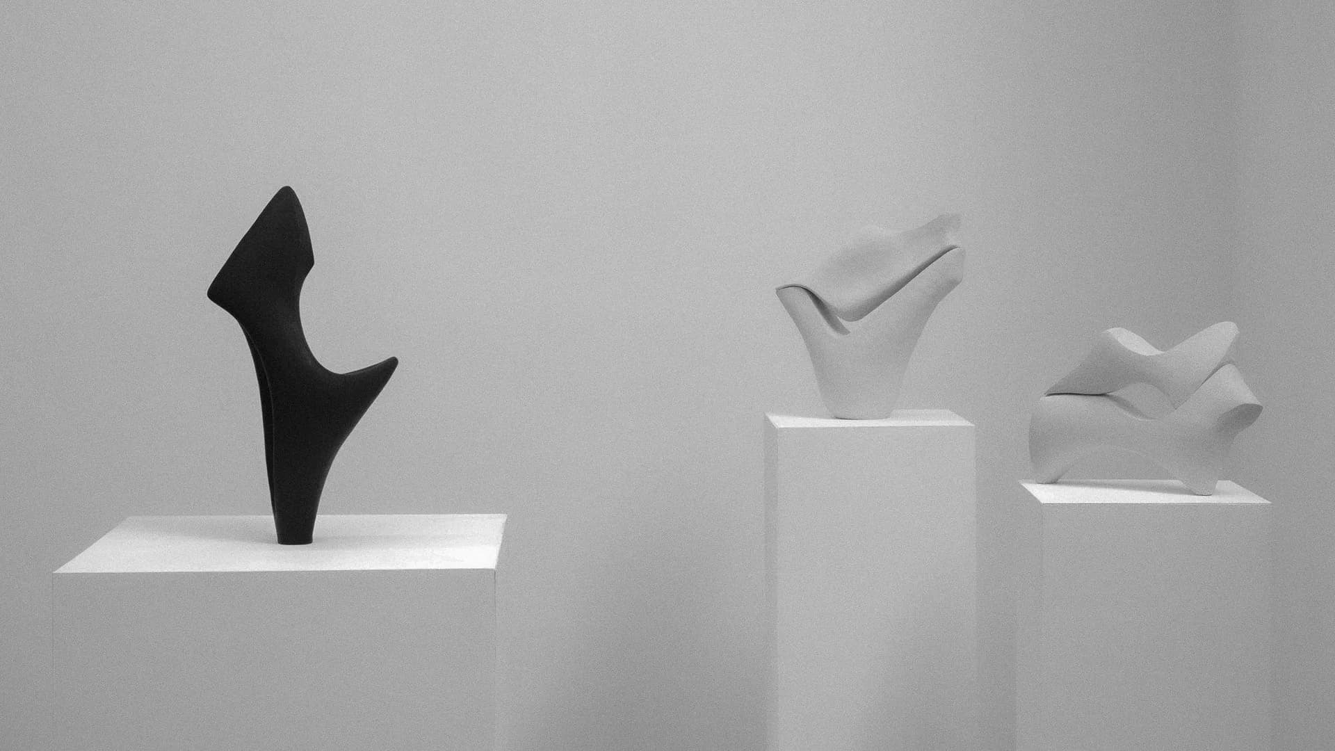 Abstract geometric composition featuring black curved form and white planar elements with sharp shadows on neutral ground, by Kassandra Thatcher.