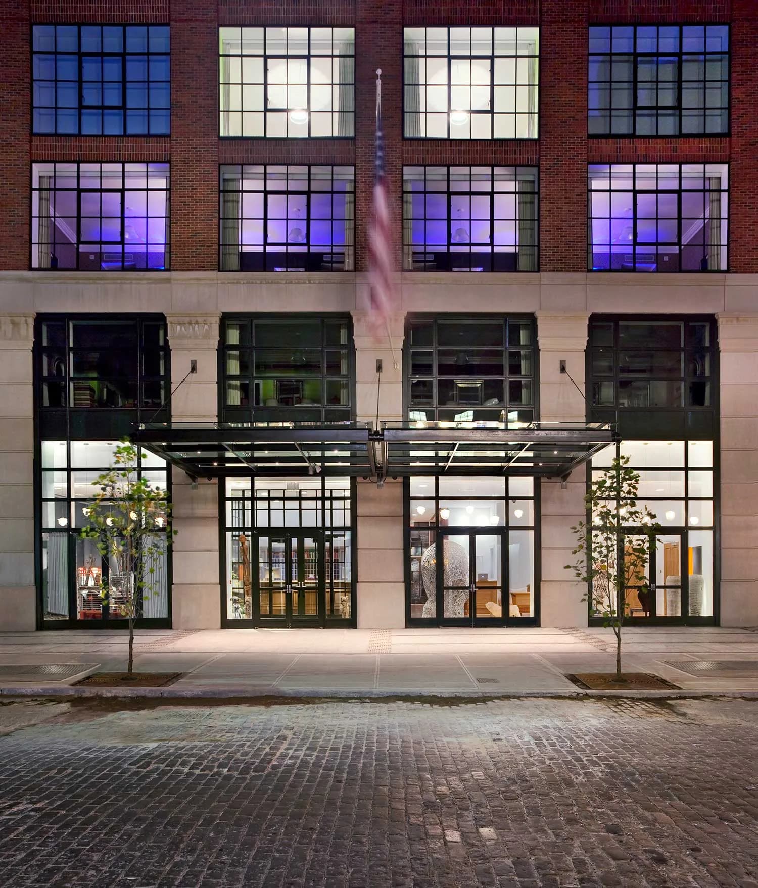 Modern storefront facade with large windows, black framing, and illuminated purple lighting on upper floors, designed by Katie Cole.