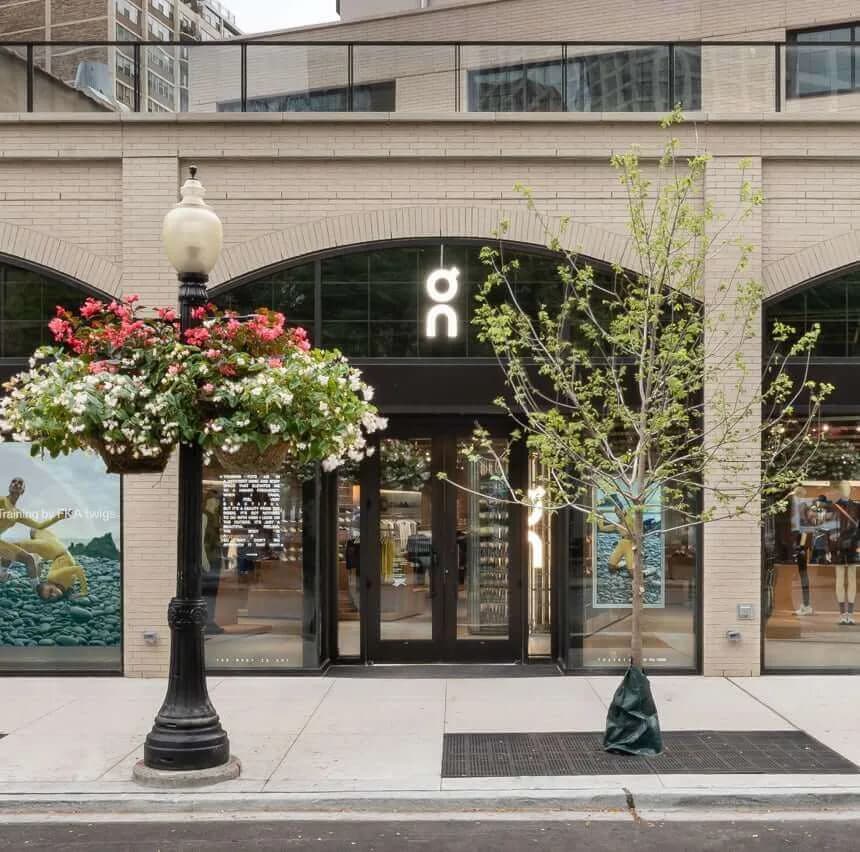 Storefront facade with arched windows, brick exterior, and vibrant hanging flower baskets, designed by EunHea Kim.