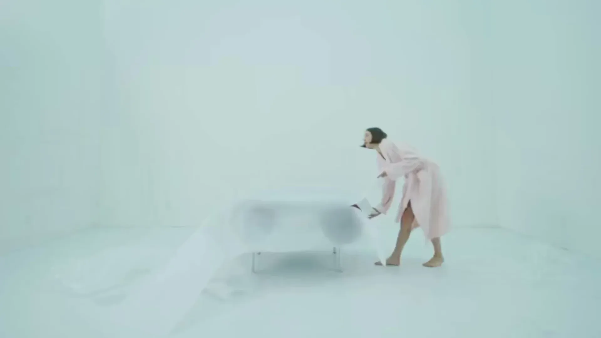 Minimalist snow-covered landscape with a figure in pale pink clothing and a small metallic structure, featuring ethereal ghosted figures and synthetic lighting characteristic of architectural visualization by Kouros Maghsoudi.
