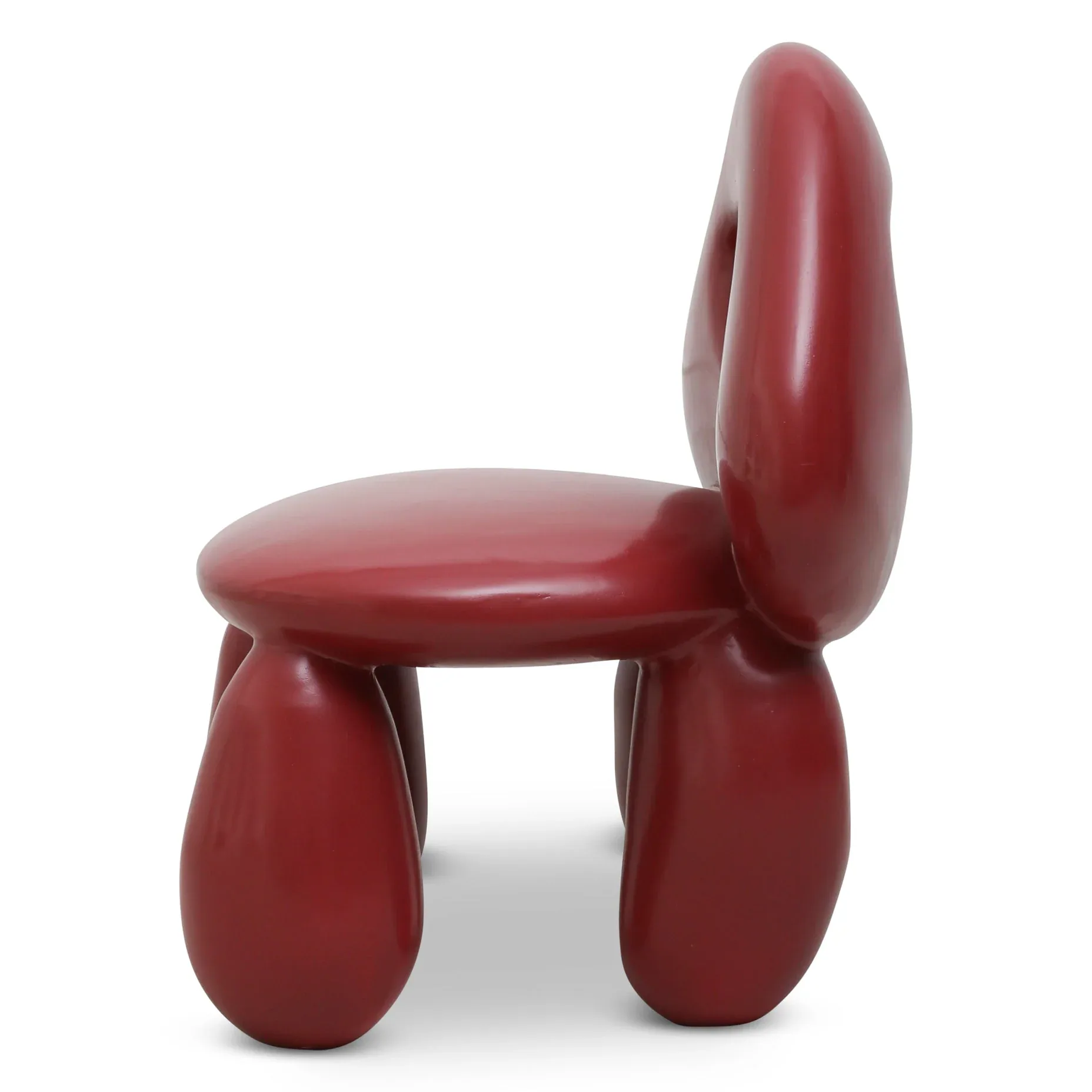 Red sculptural chair with rounded organic forms and hollow openings, featuring a glossy finish and curved backrest, by Kouros Maghsoudi.